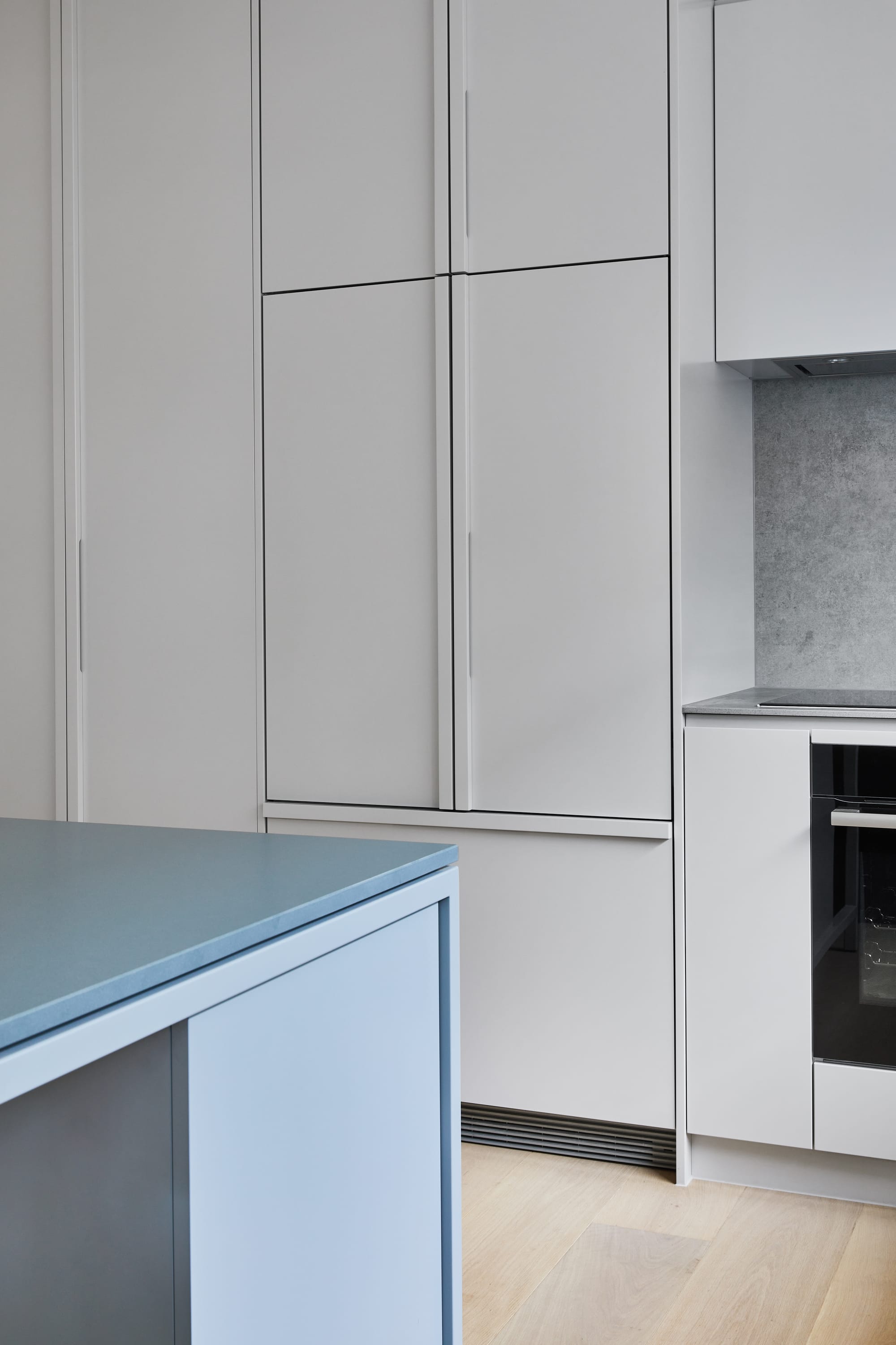 The Full Monty by FYC Architects. Photography by Stephanie Rooney. Kitchen cabinetry in light grey tone. Blue island bench. Light timber floors. 