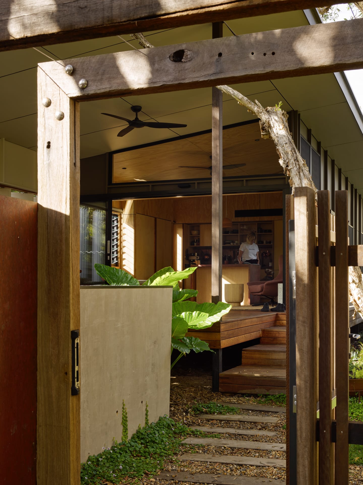 PaperBark Pod by Bark Design. Photography by Christopher Frederick Jones. Rustic wooden sleepers acting as a garden path lead to timber deck extending from open plan living area. Rustic timber fencing. 
