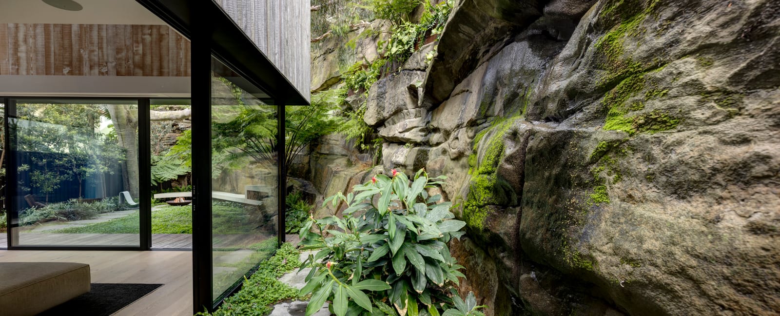 Quarry Box by MCK Architects. Photography by Brett Boardman. Landscape image of quarry rock face next to black-framed floor-to-ceiling windows.