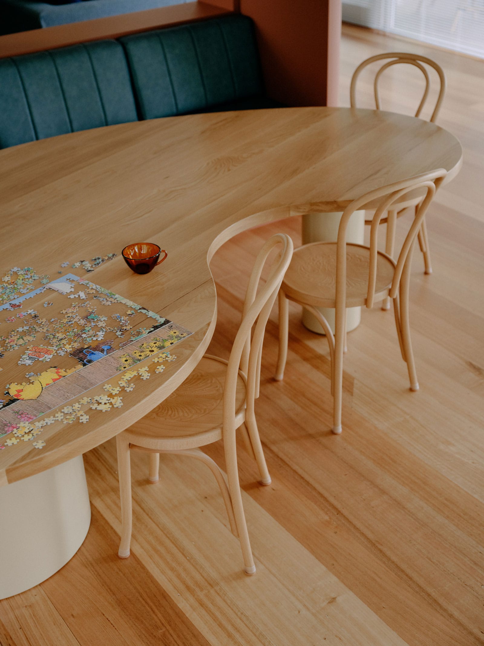 Selby House by Placement. Photography by Tom Ross. Kidney shaped timber dining table. Timber floors. Blue upholstered bench seating.