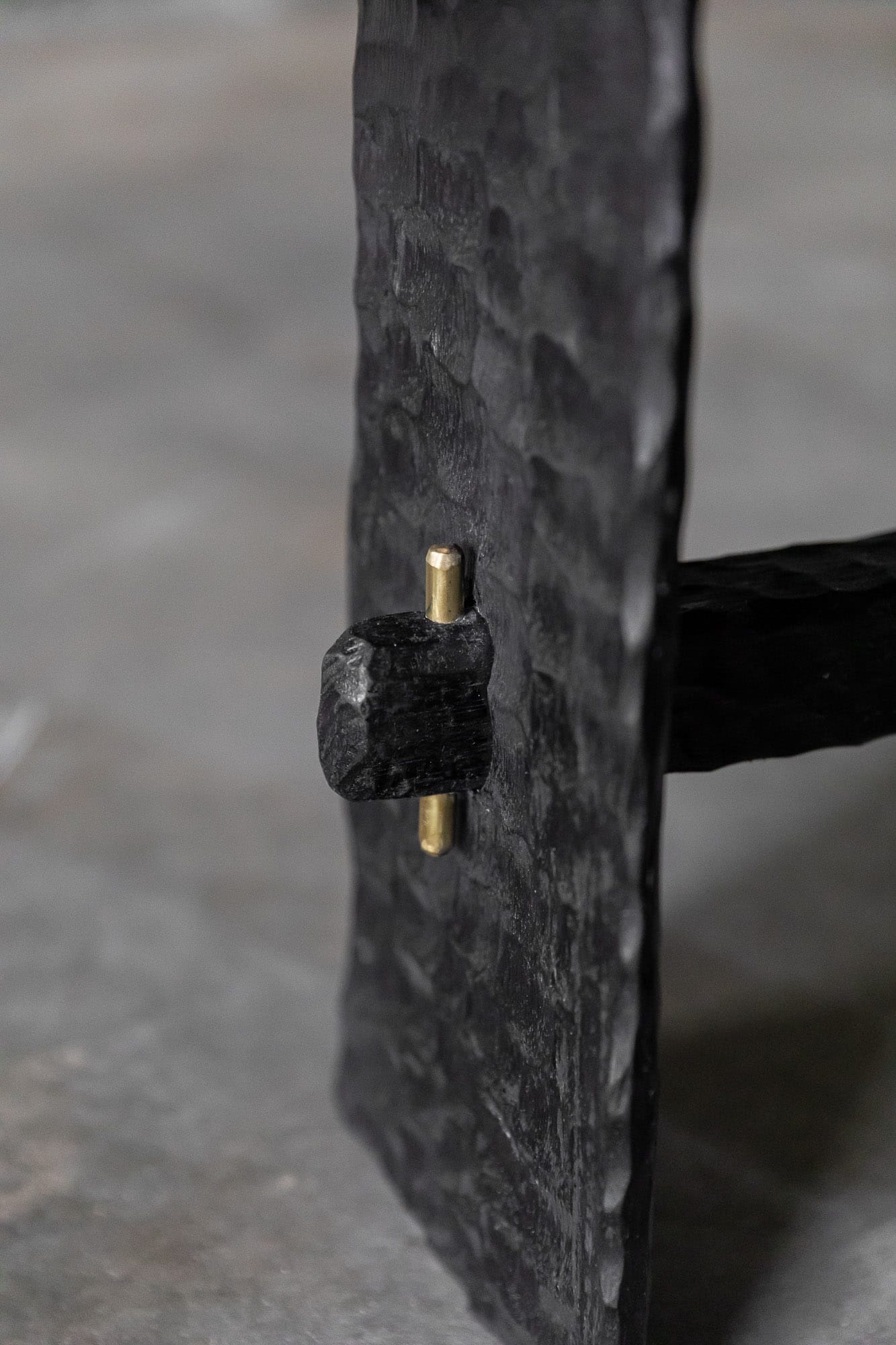 A detail shot of one of Two Blue Boys Furniture showing the brass detailing and dark timber, textured finish