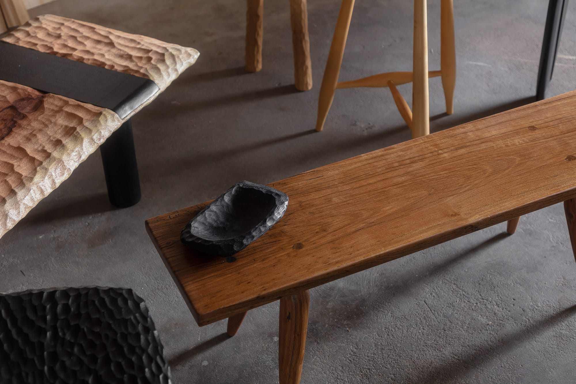 Two Blue Boys. Copyright of Two Blue Boys. Aerial view of array of timber tables and benches on concrete floors. Varied timber hues and textures. Decorative black bowl.