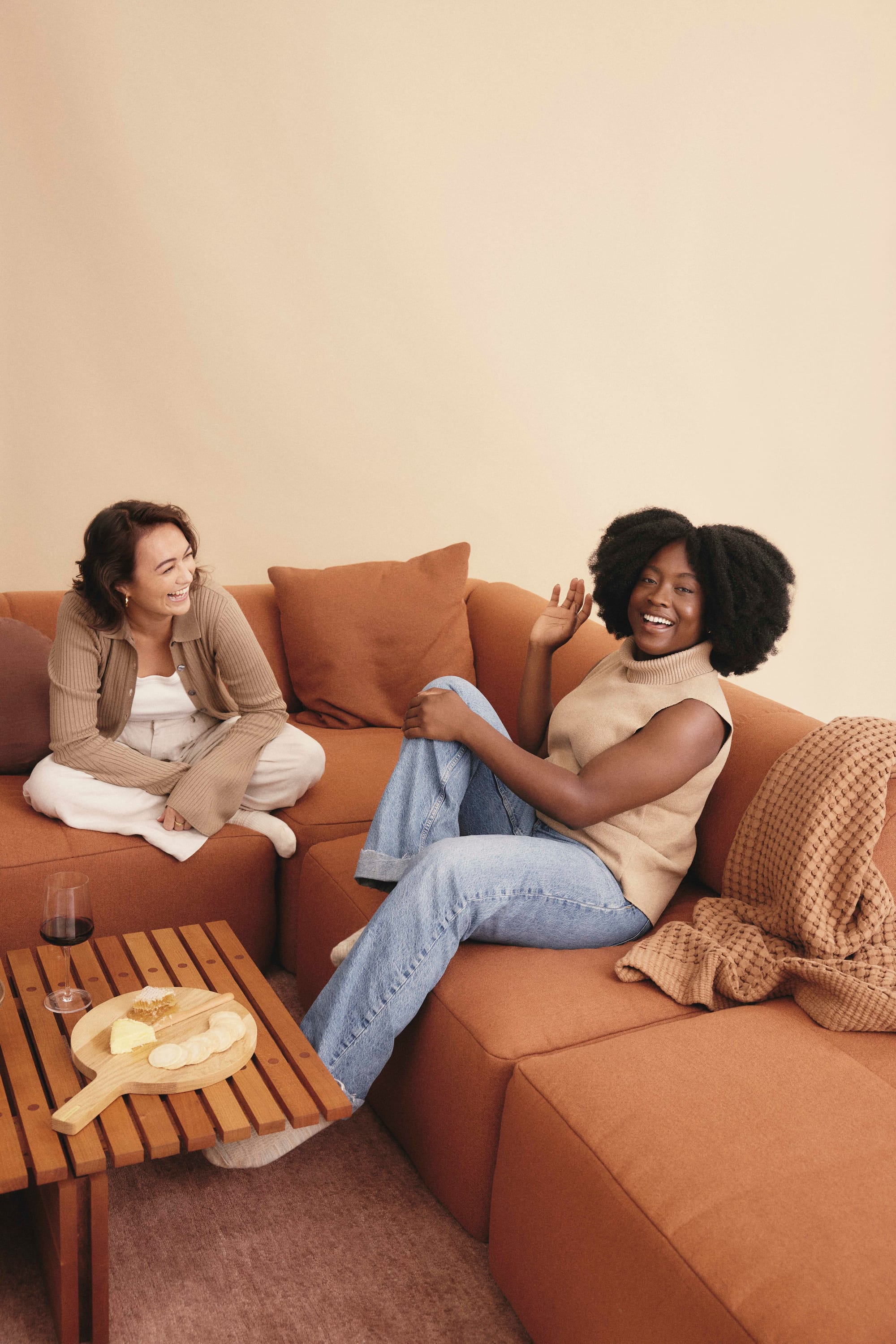 Eva Everyday Sofa. Copyright of Eva. Two young women on terracotta modular lounge.