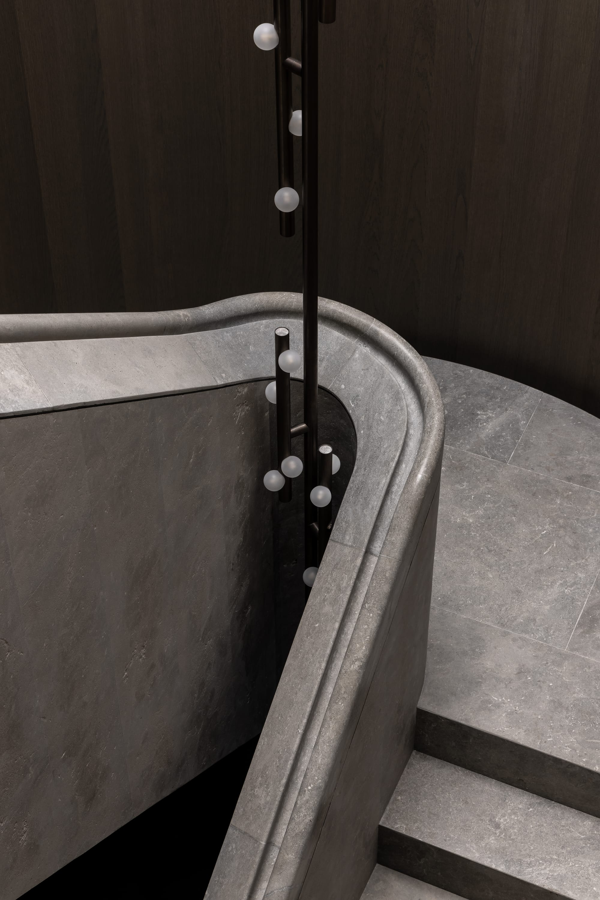 Cliff House by Finnis Architects. Photography by Timothy Kaye. Detail of curved stone balustrade on staircase. Stone steps, floor, balustrade. Timber veneer wall.