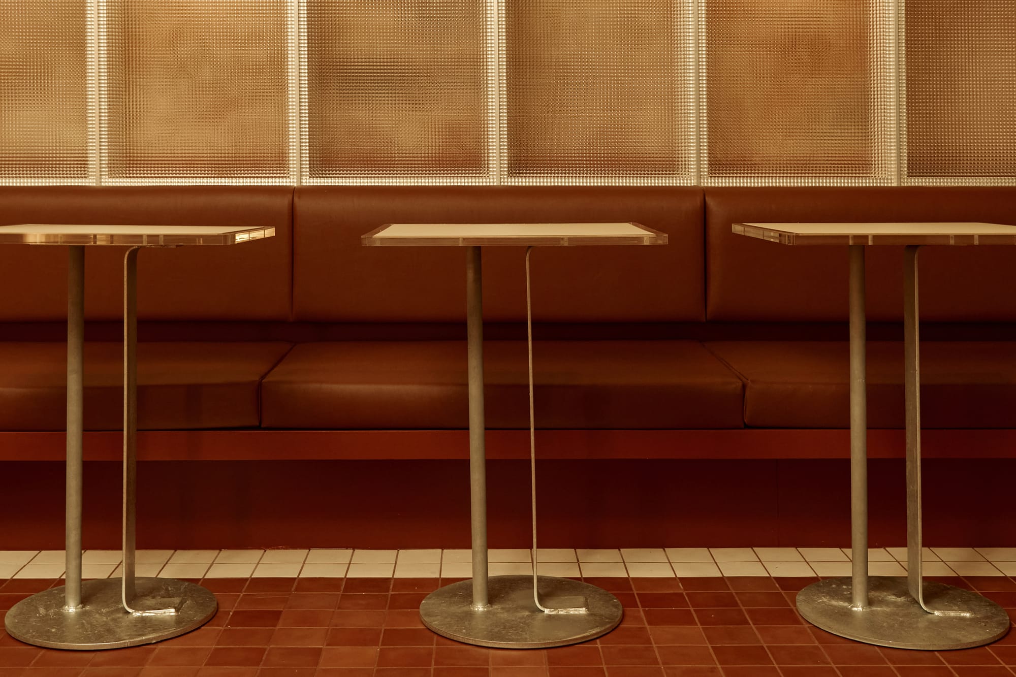 S'WICH Bondi by Studio Shand. Photography by Claudia Smith. Brown leather bench seating with vintage metal tables. Brown and white tiled floor. 