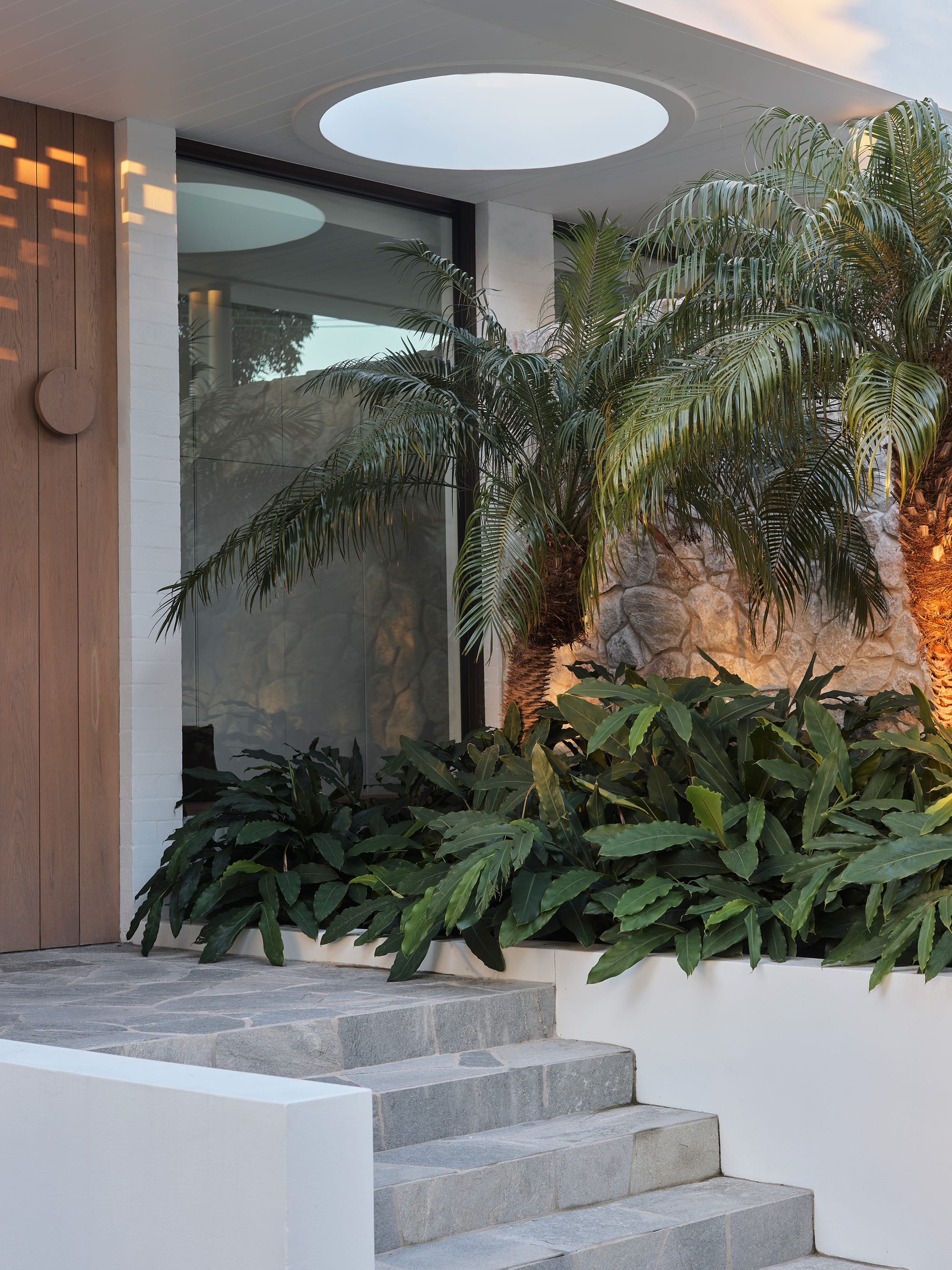 Warren House by CM Studio. Photography by Nic Gossage. Timber front door with slate paver steps. Garden bed with ferns and stone wall.