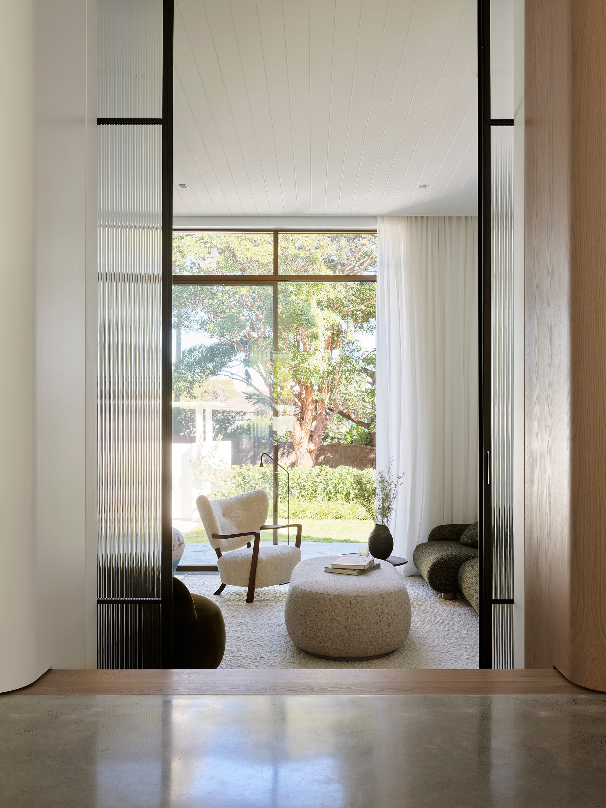 Warren House by CM Studio. Photography by Nic Gossage. Sunken living room with floor-to-ceiling windows. Rounded sofa and armchairs.