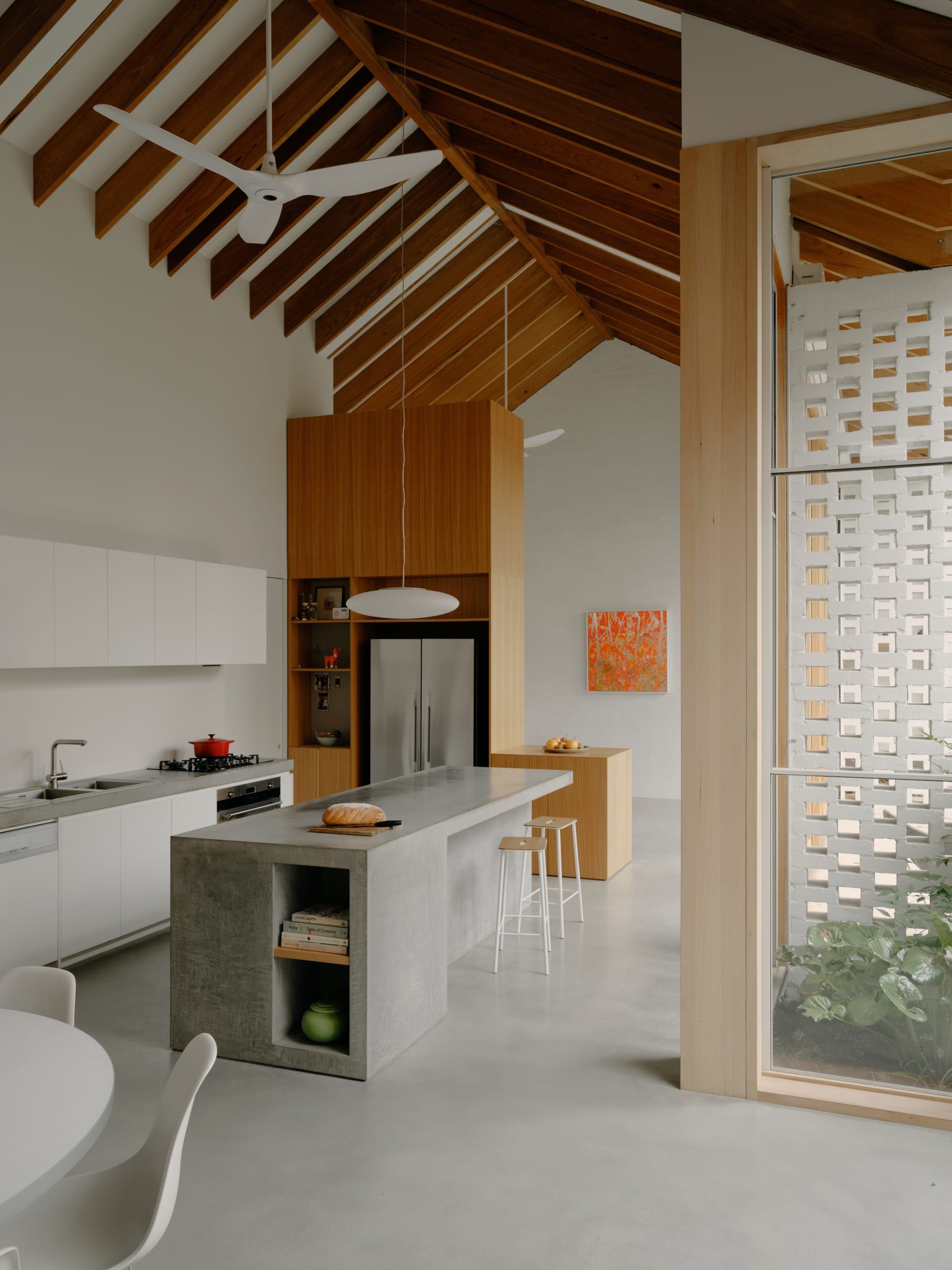 Corymbia by Karen Abernethy Architects. Photography by Tom Ross. Kitchen with polished concrete floor and island bench. Concrete countertops. Cathedral ceiling with exposed timber beams. 