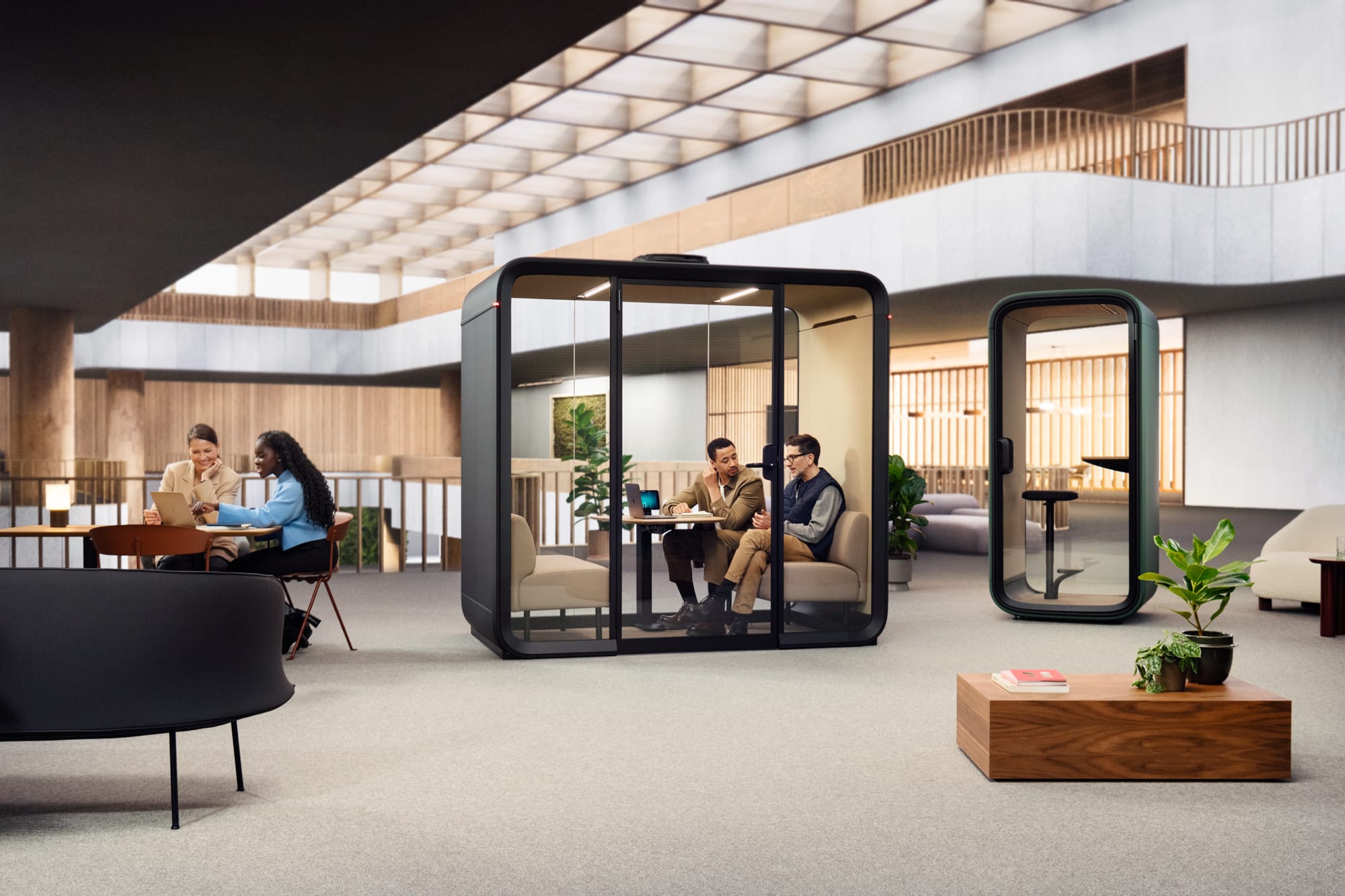 Framery Smart Pod. Copyright of Framery. Two men sitting in large black work hub on corporate floor. Single work hub to right. 