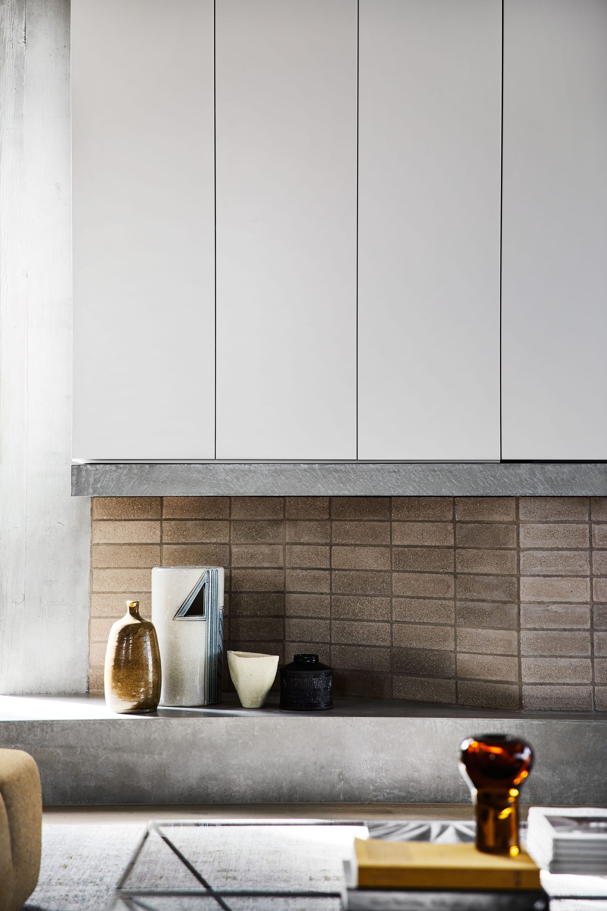 The Split Home by Seidler Group. Copyright of Seidler Group. Integrated concrete display plinth on side of brick and concrete fireplace in residential living space. 