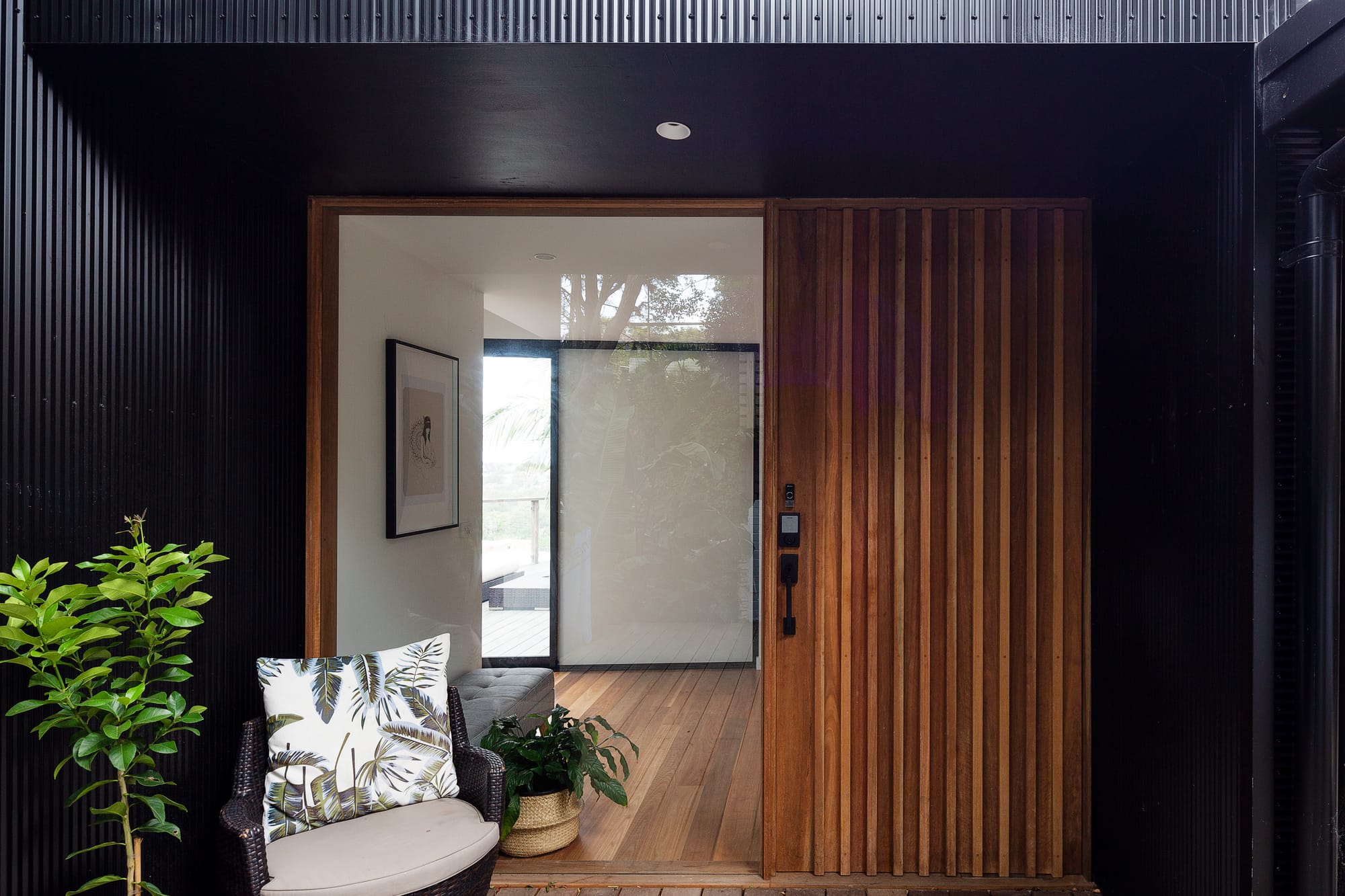 Tree House by North By North. Photography by Simon Whitbread. Timber front door entrance to home. Black clad timber walls. Timber floors inside. 