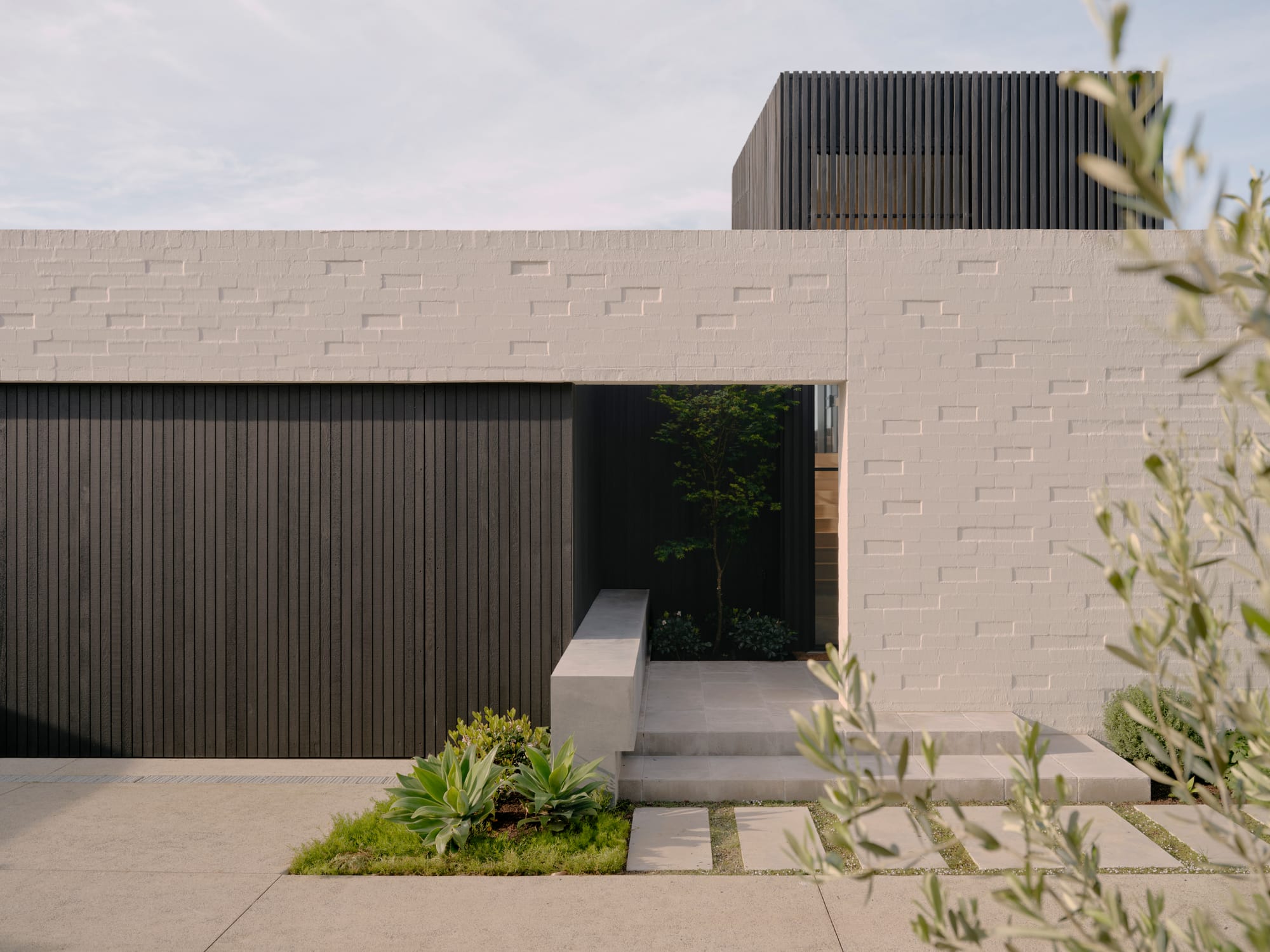 Bassano by Tom Robertson Architects. Photography by Derek Swalwell. Bedroom with cathedral ceilings with white timber exposed beams. Black fireplace built into cabinetry made of black patina metal. 