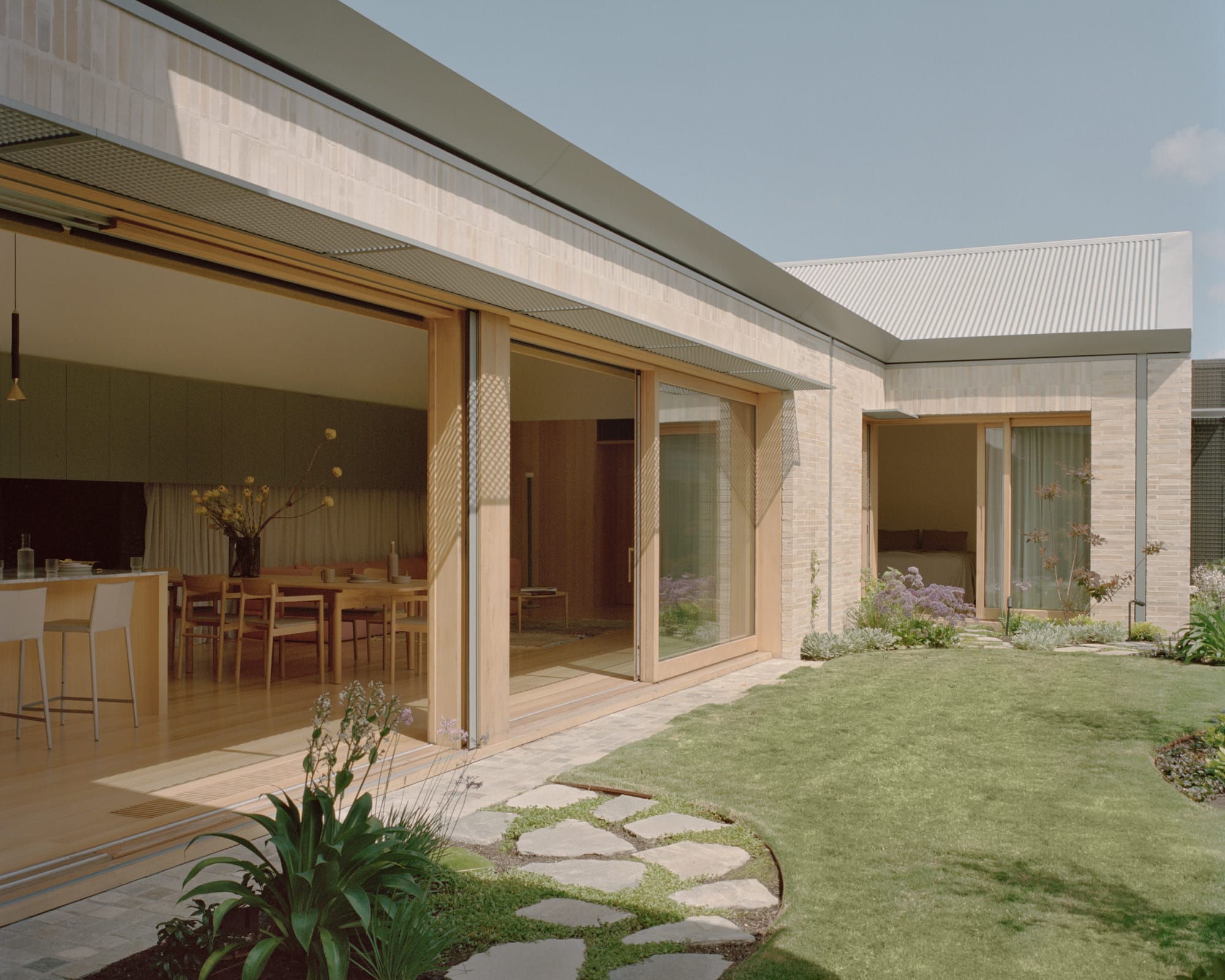 Gable Park by Weaver+Co Architects. Photography by Tasha Tylee. Enclosed exterior courtyard opens up from open plan living, kitchen and dining area and bedroom. Green grass and paved foothpaths. 