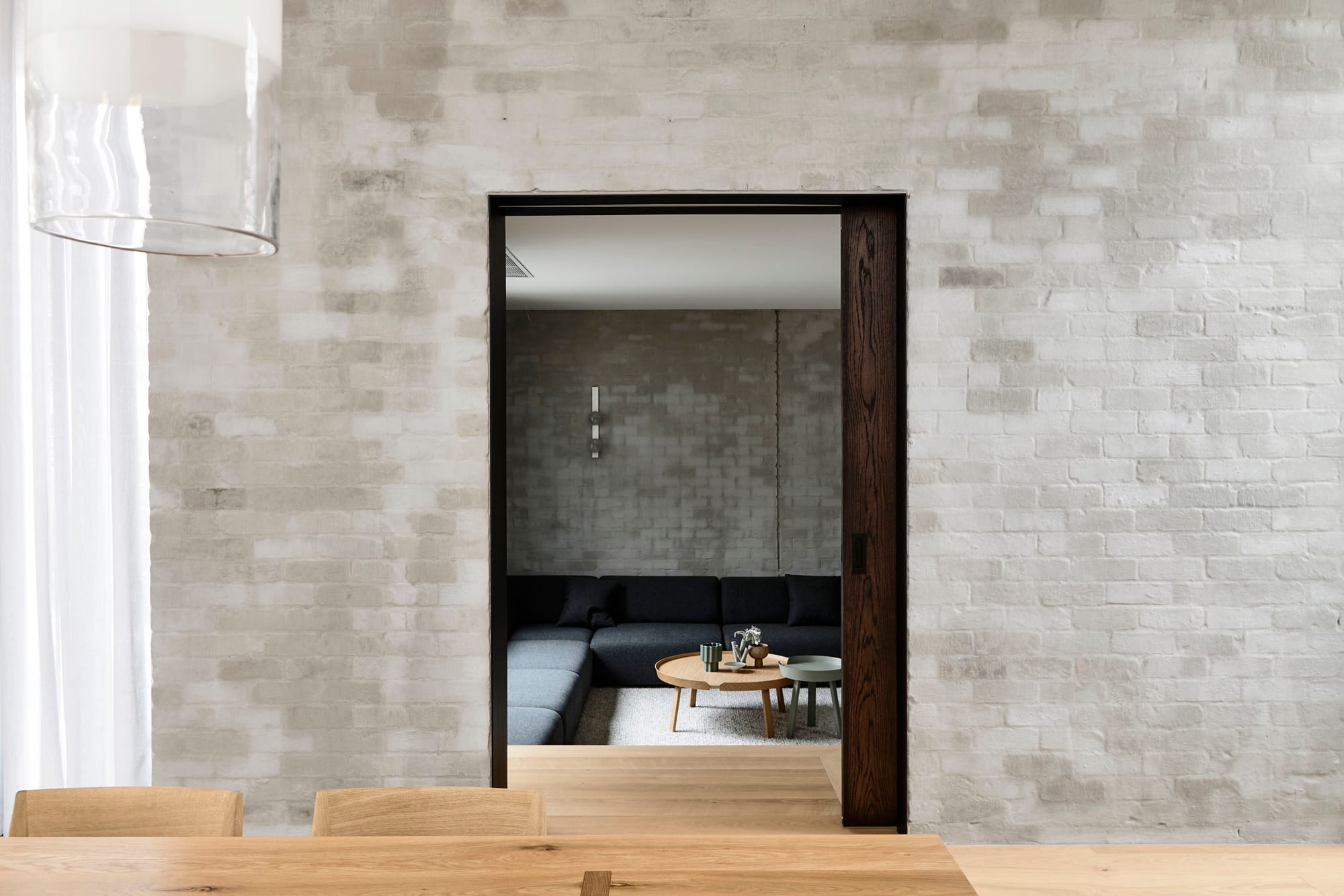 Silvertop House by Tom Robertson Photography. Photography by Derek Swalwell. Interior courtyard with a tree, lush shrubs and vines climbing up walls. Hallway and stairwell with timber flooring through doorway to right. 