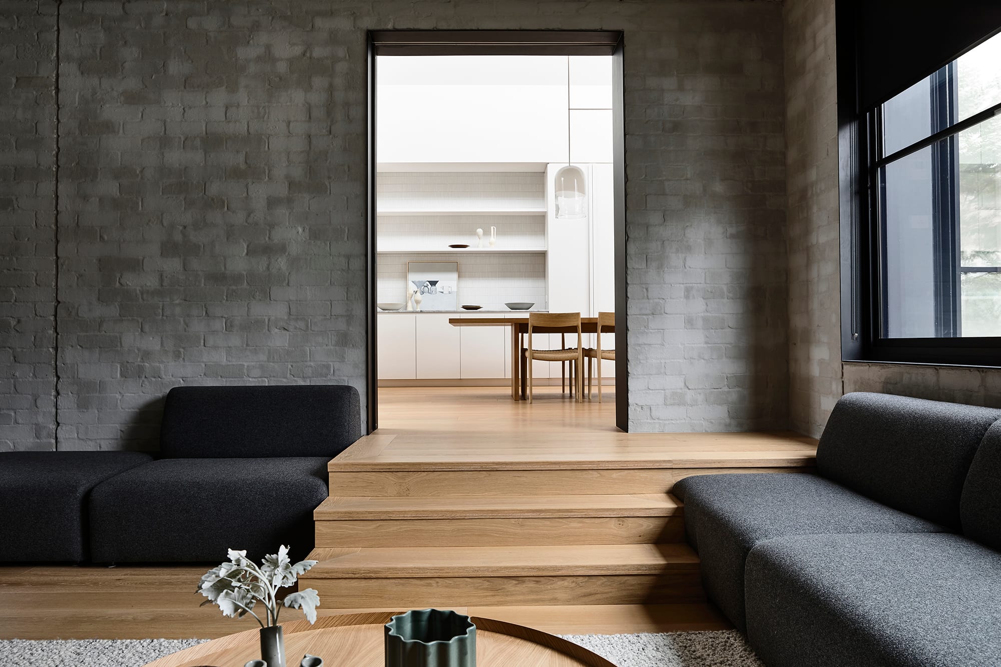 Silvertop House by Tom Robertson Photography. Photography by Derek Swalwell. Stairway and hallway with timber flooring and balustrade. Timber framed glass sliding door to left opens onto lush indoor courtyard. 