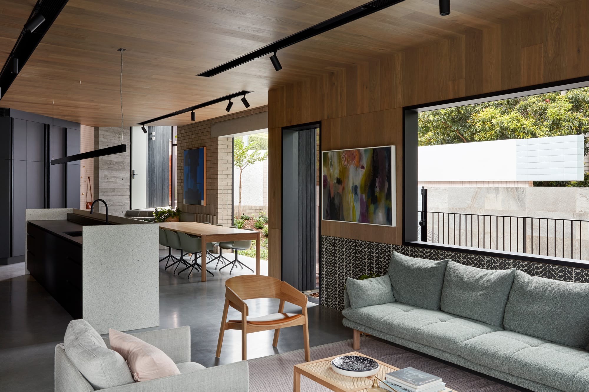 Uxbridge House by Tim Stewart Architects. Photography by Christopher Frederick Jones. Open plan living, kitchen and dining space with timber walls and ceiling. Polished concrete flooring. Doors and windows overlook gardens. 
