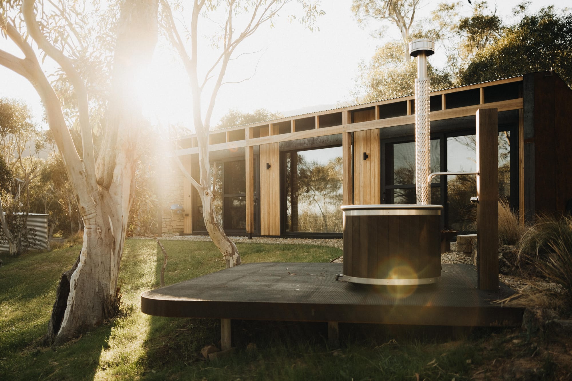 Crafters Eco-Cabins. Image copyright of Crafters. Timber clad cabin in background, external timber bathtub on timber deck in foreground.