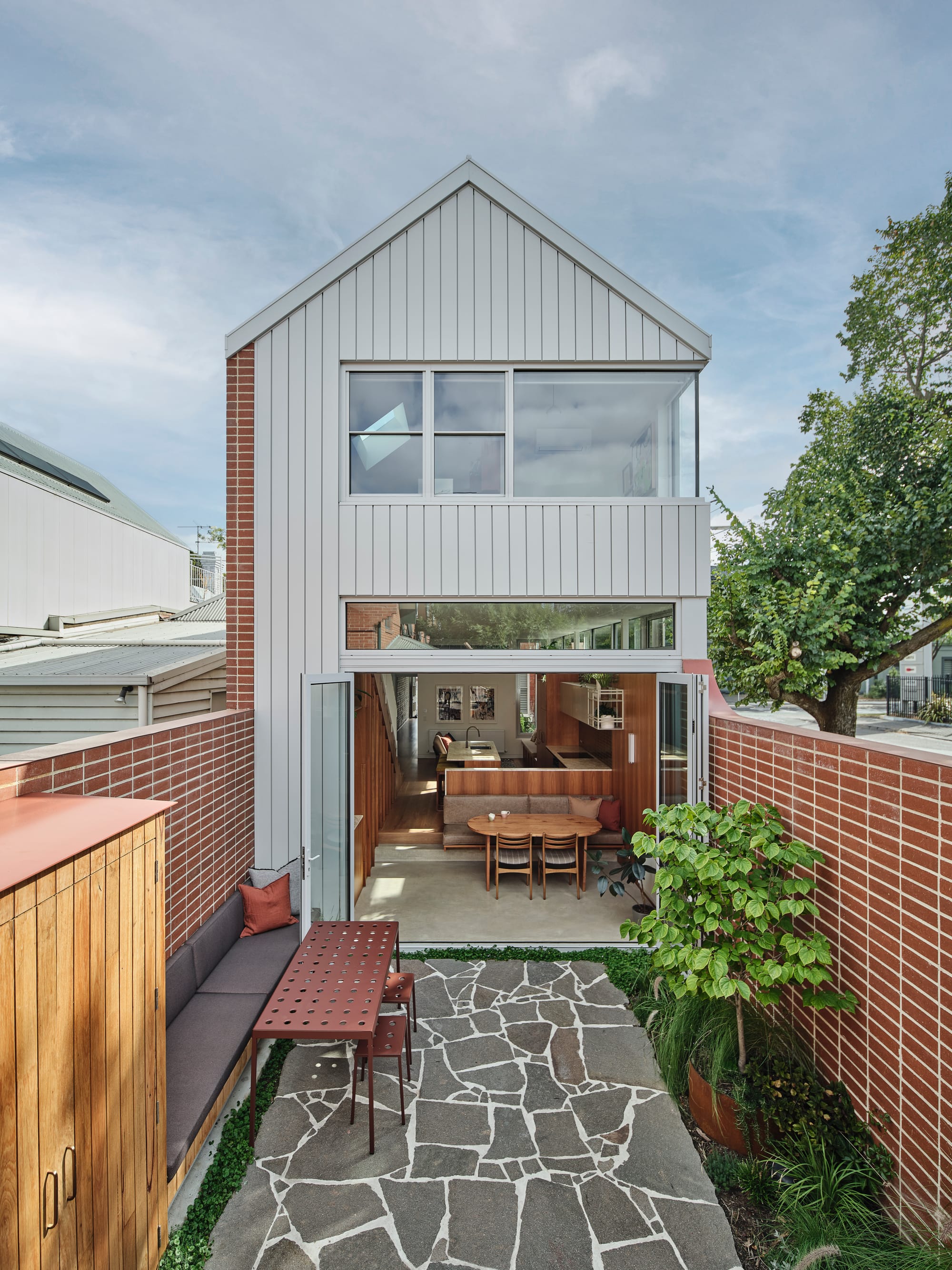 House Northroy by True Story. Photography by Dean Bradley. Rear facade of double storey terrace home with paved courtyard and brick walls. White clad facade.