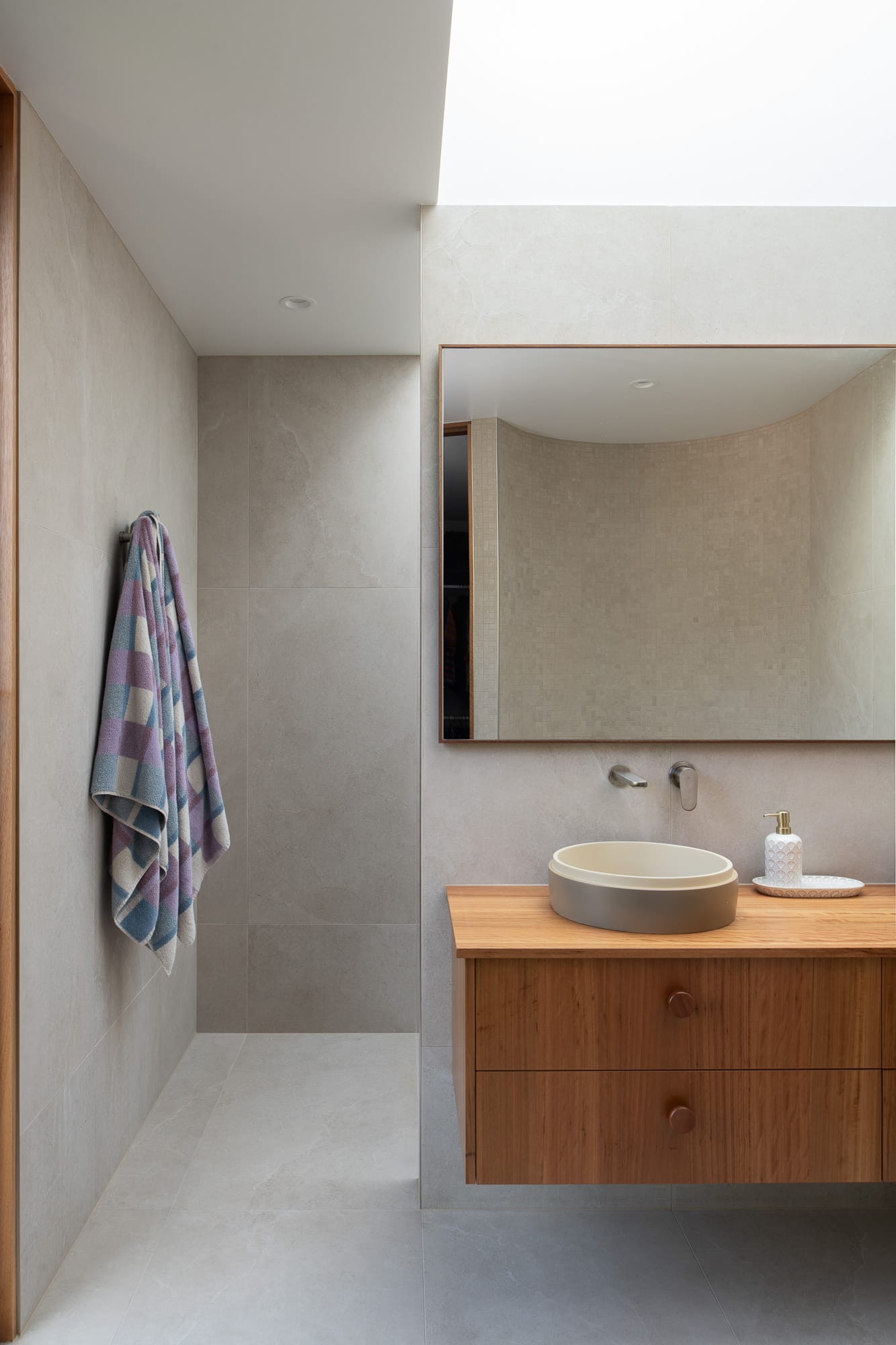 Mortlock Timber Series: The Milldam. Photography by Anjie Blair.  Bathroom with grey stone tiled walls and timber floating cabinet below large mirror. 