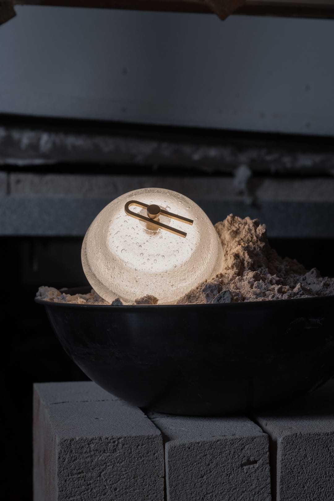 Point Five by South Drawn. Image copyright of South Drawn. Domed sconce emitting warm light sitting in black bowl of ash on grey brick wall.