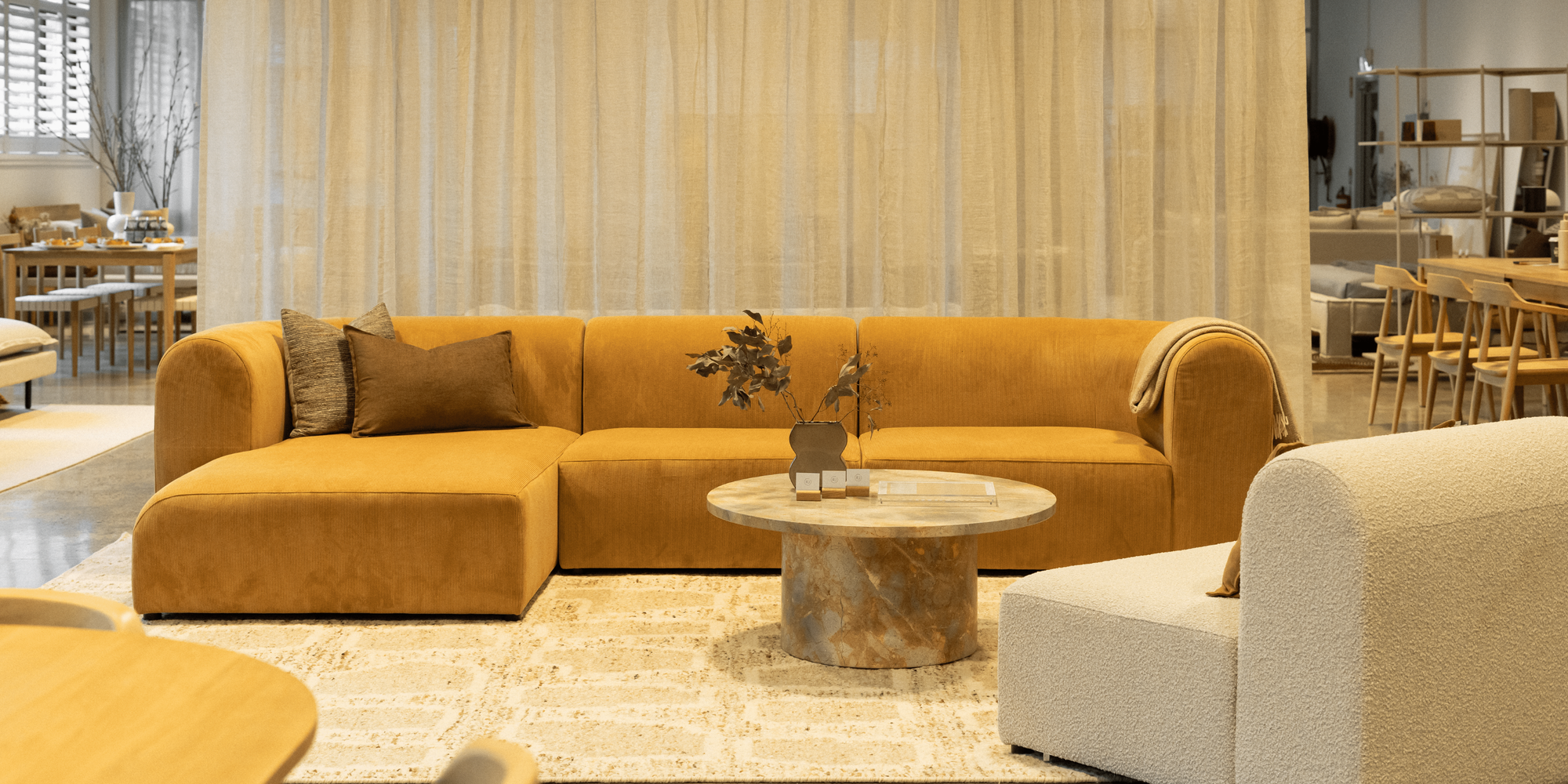 Tan suede bed frame with maroon linen. Jute floor rug and timber sideboard.