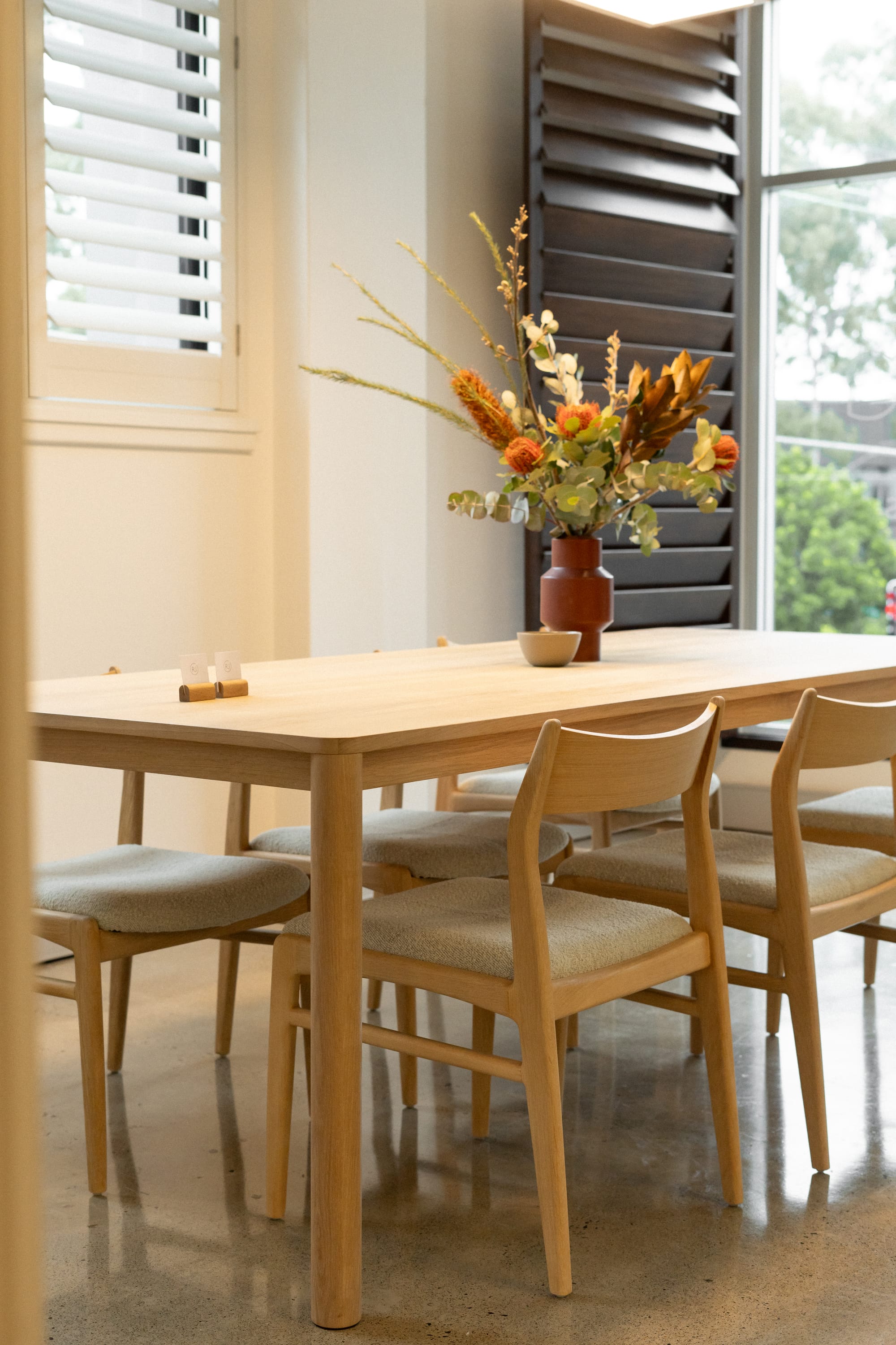 RJ Living's New Sydney Retail Space. Photography by Nathan Oakley. Timber dining setting with boucle chairs. Polished concrete floors.