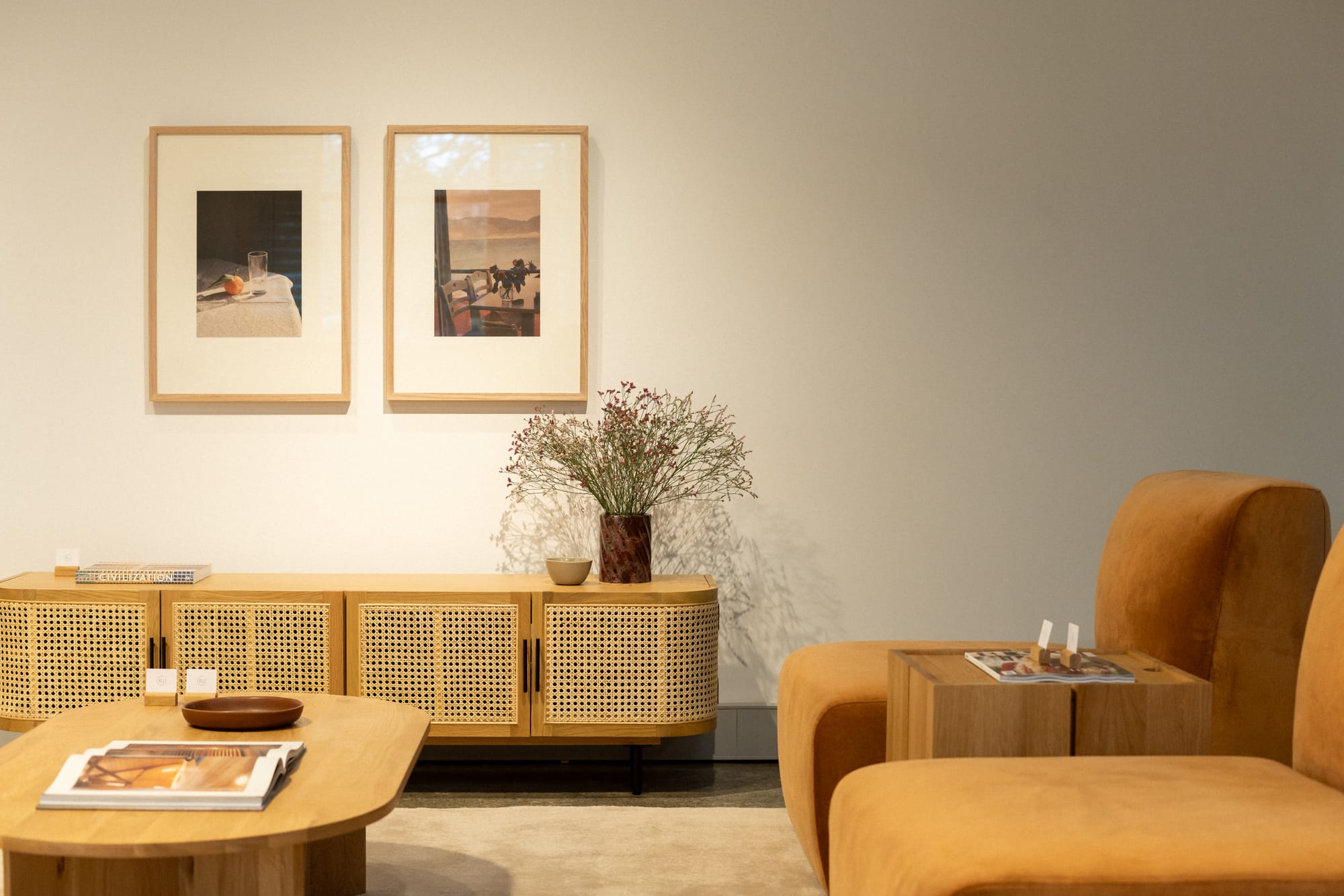 RJ Living's New Sydney Retail Space. Photography by Nathan Oakley. Living space with rattan and timber sideboard. Timber coffee table and orange armchairs.