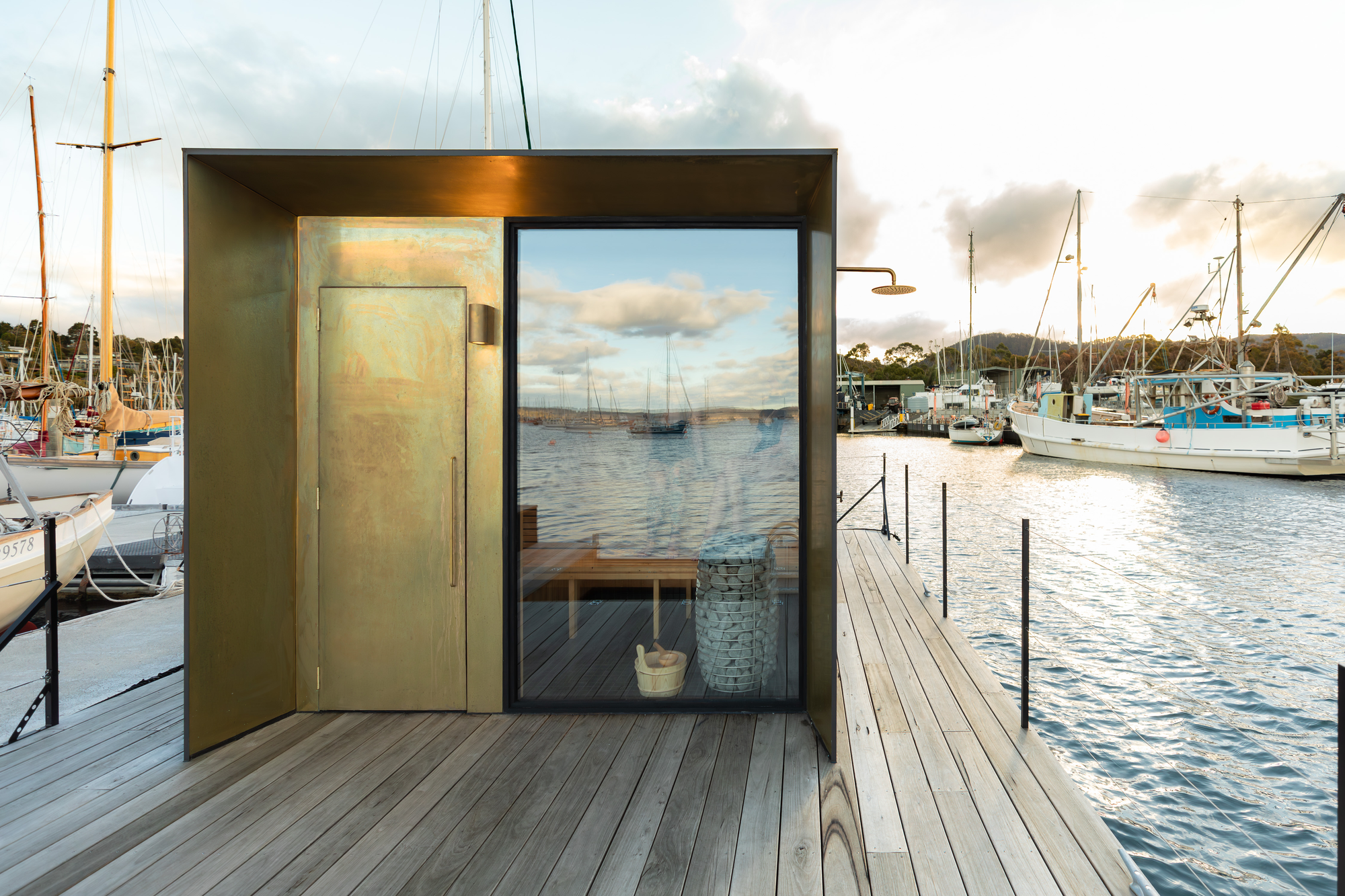 Sauna Boat Tasmania. Photography by Natasha Mulhall. Bronze wrapped sauna with timber deck.