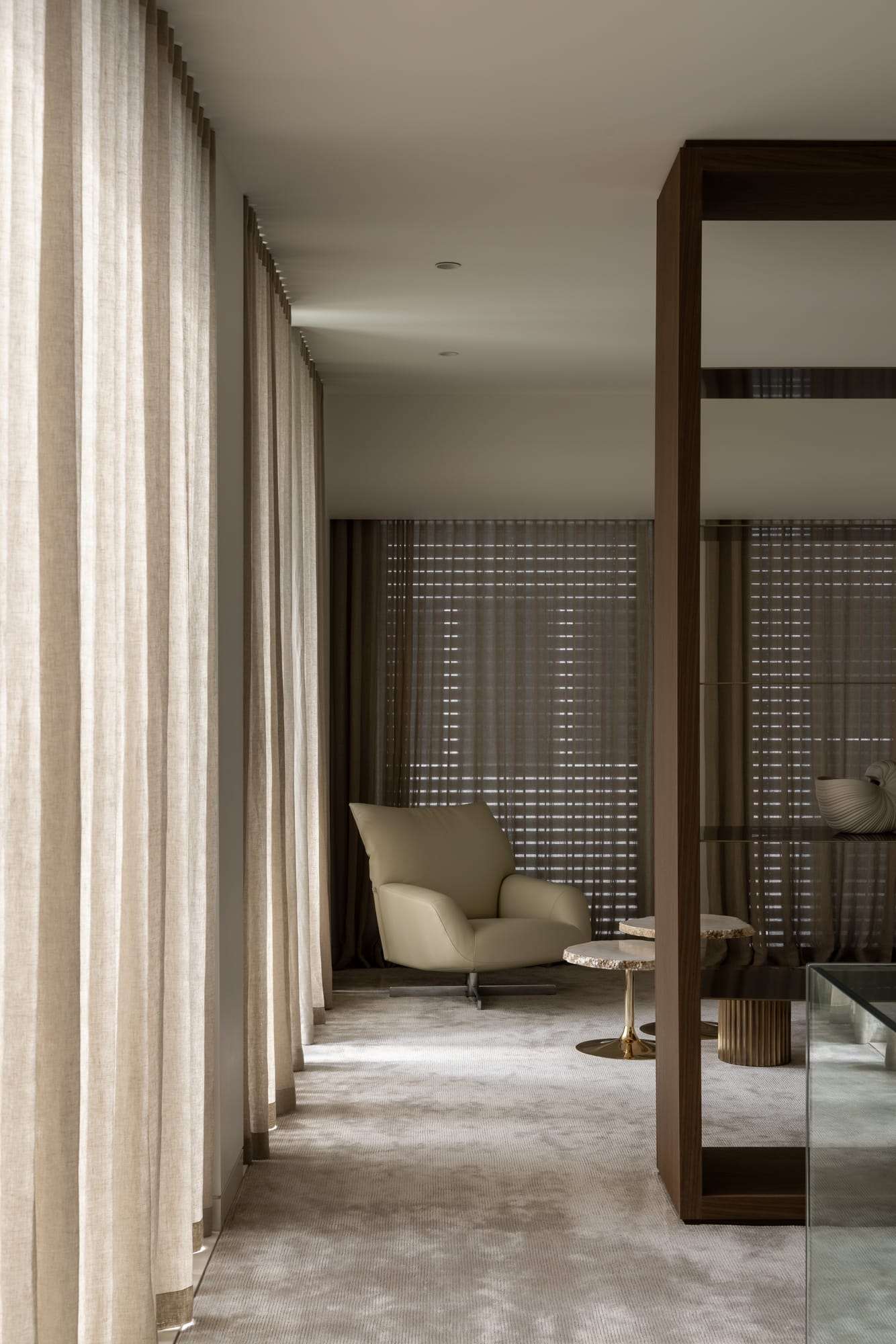 An interior shot of a well styled sitting room with an occasional chair and a linen curtain closed to the left
