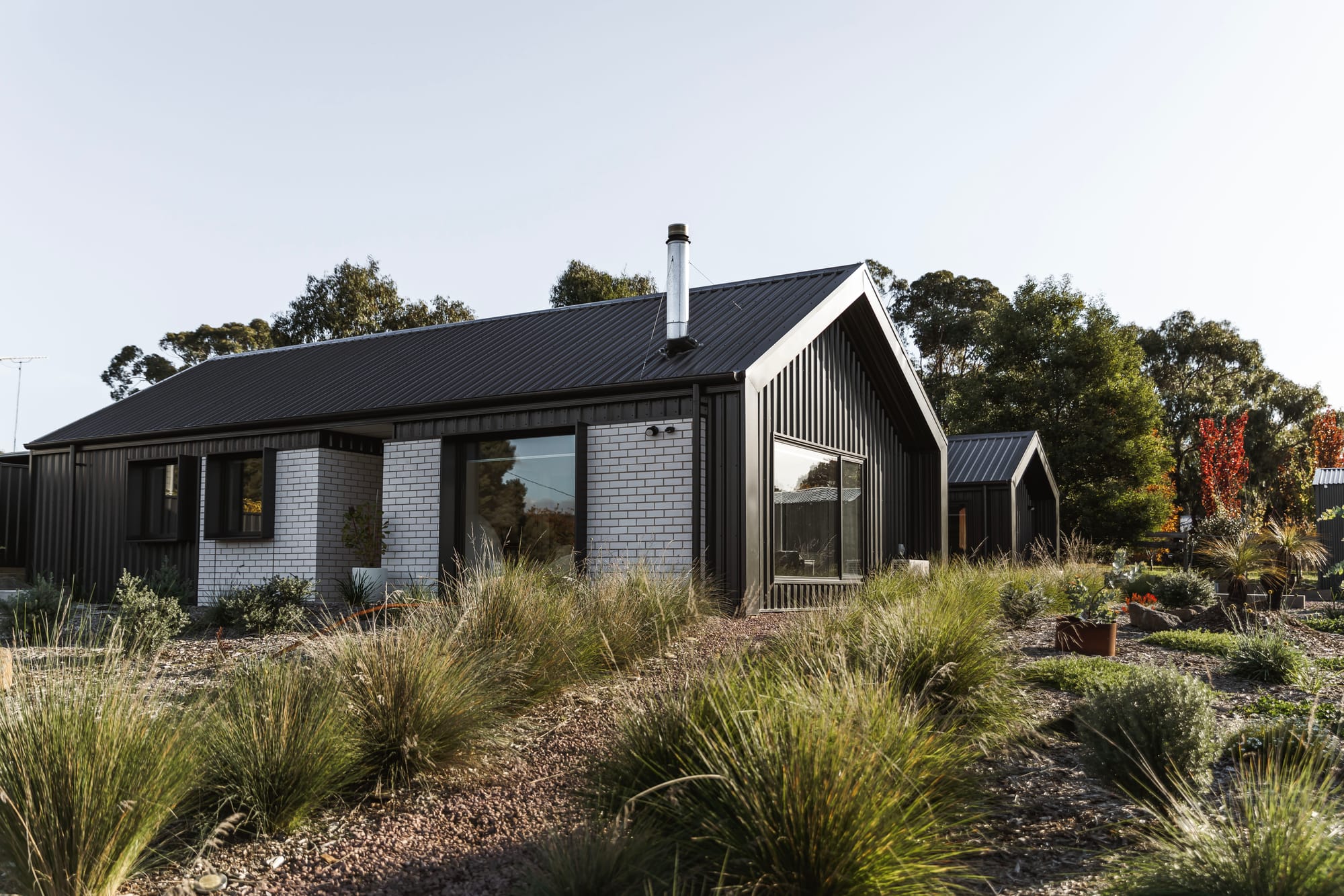 An external shot of the front door of Forrest Haus Retreat with a woman walking and scattered landscape in the foreground