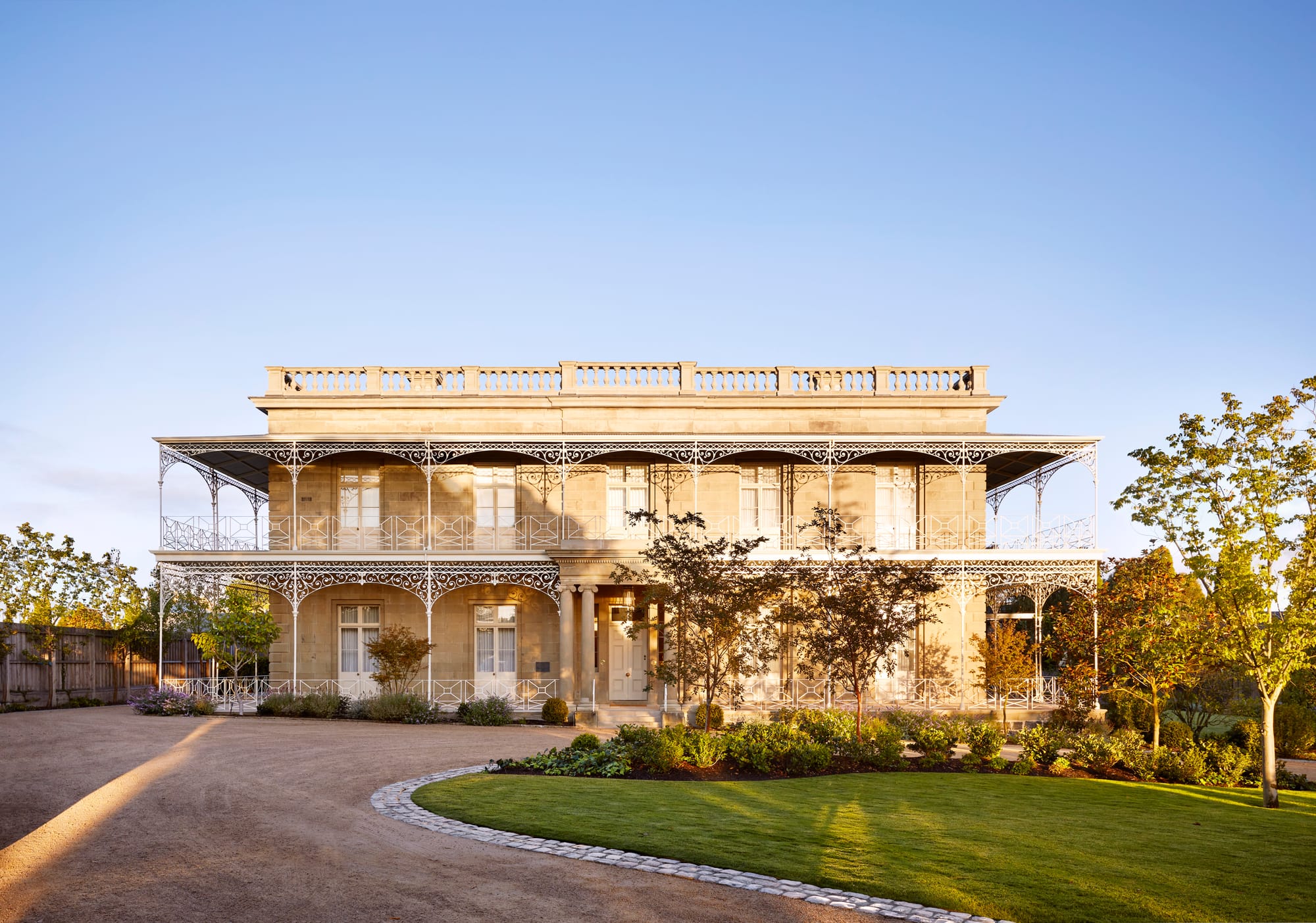Armytage House by Myles Baldwin Design. View to grand estate building with pathway and greenery.