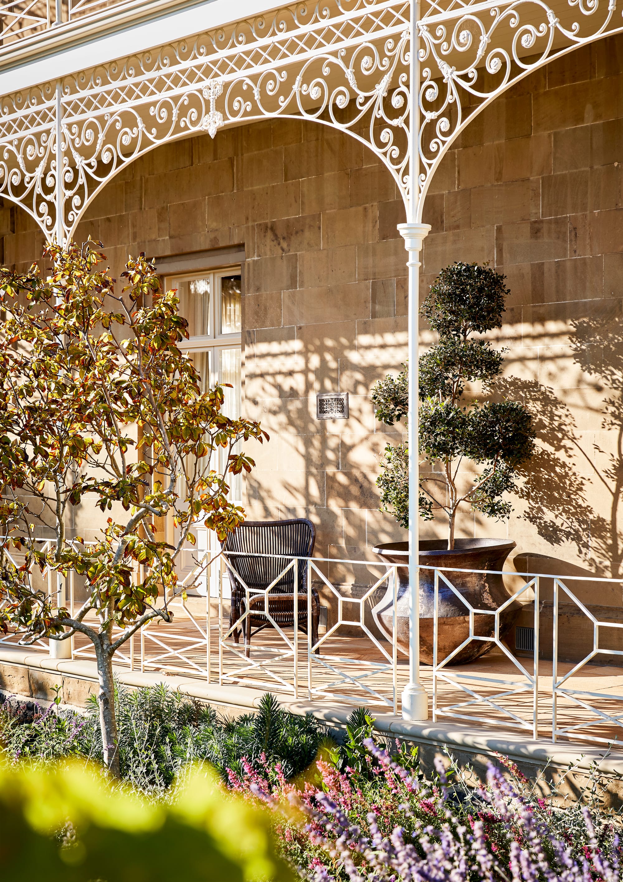Armytage House by Myles Baldwin Design. Victorian house façade featuring white railing, surrounded by greenery.