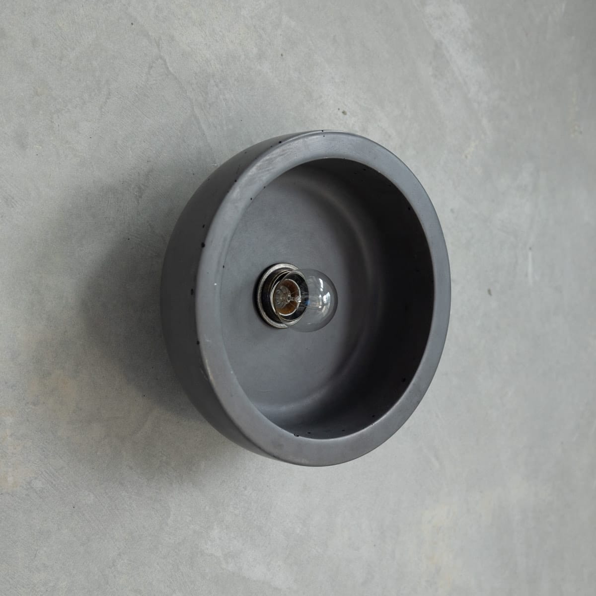 Small Hakea Sconce in Charcoal. Image copyright of Crete Studio. Dark grey bowl lighting wall fixture on concrete wall.