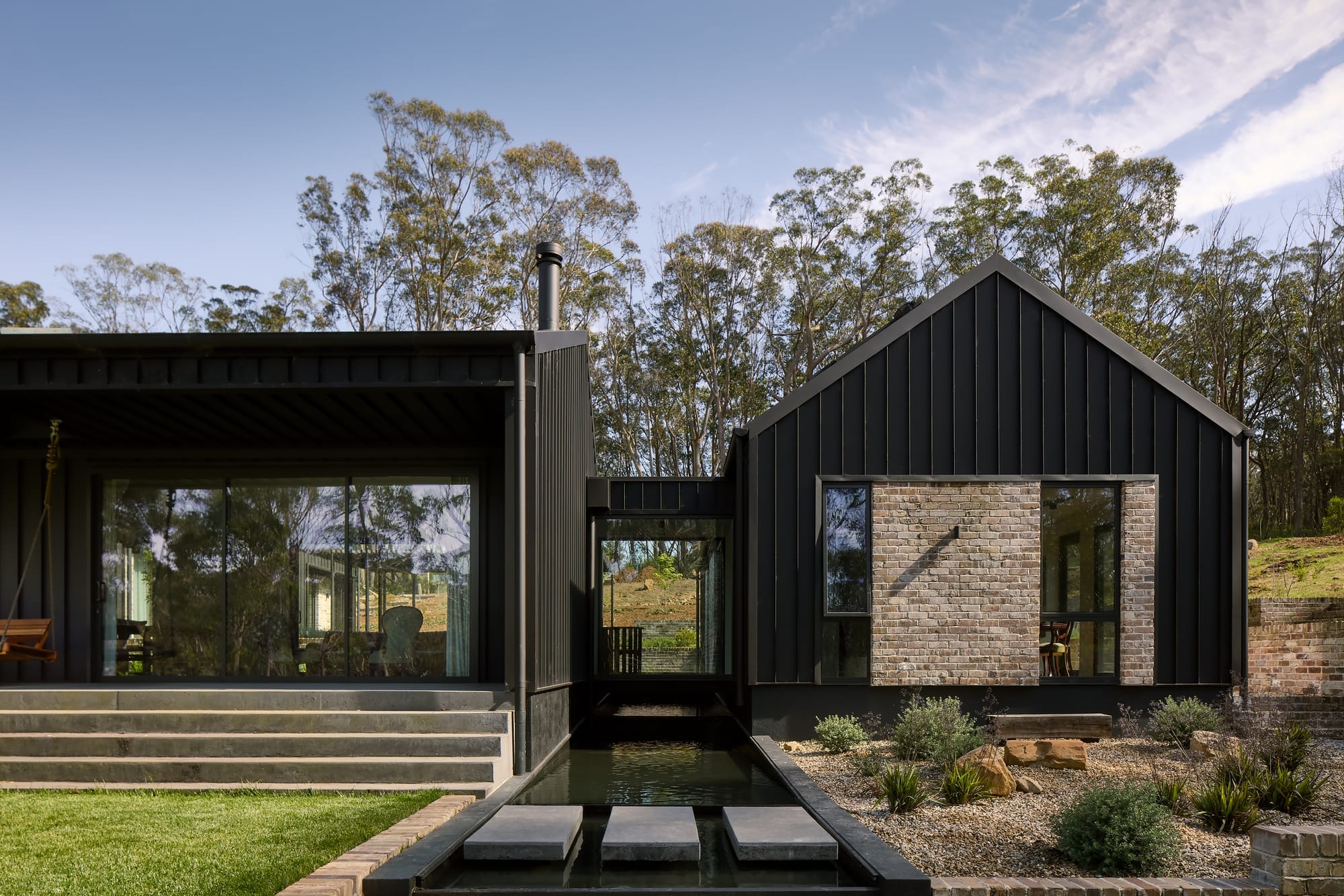 The Ripple House by Marker Architecture. Photography by Simon Whitbread. Side of home with sandstone and black timber exterior.