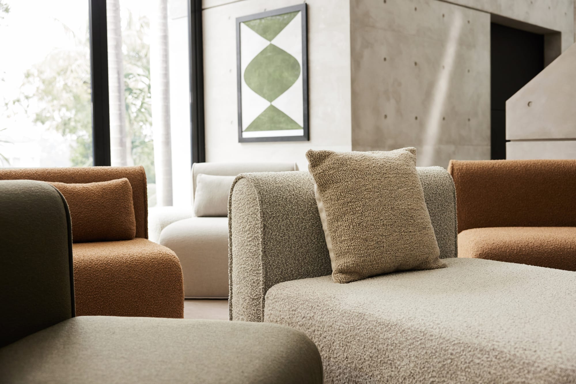 Bangalow Modular Sofa.  Close up of various colours of boucle chaise modular lounge in front of concrete paneled wall. 