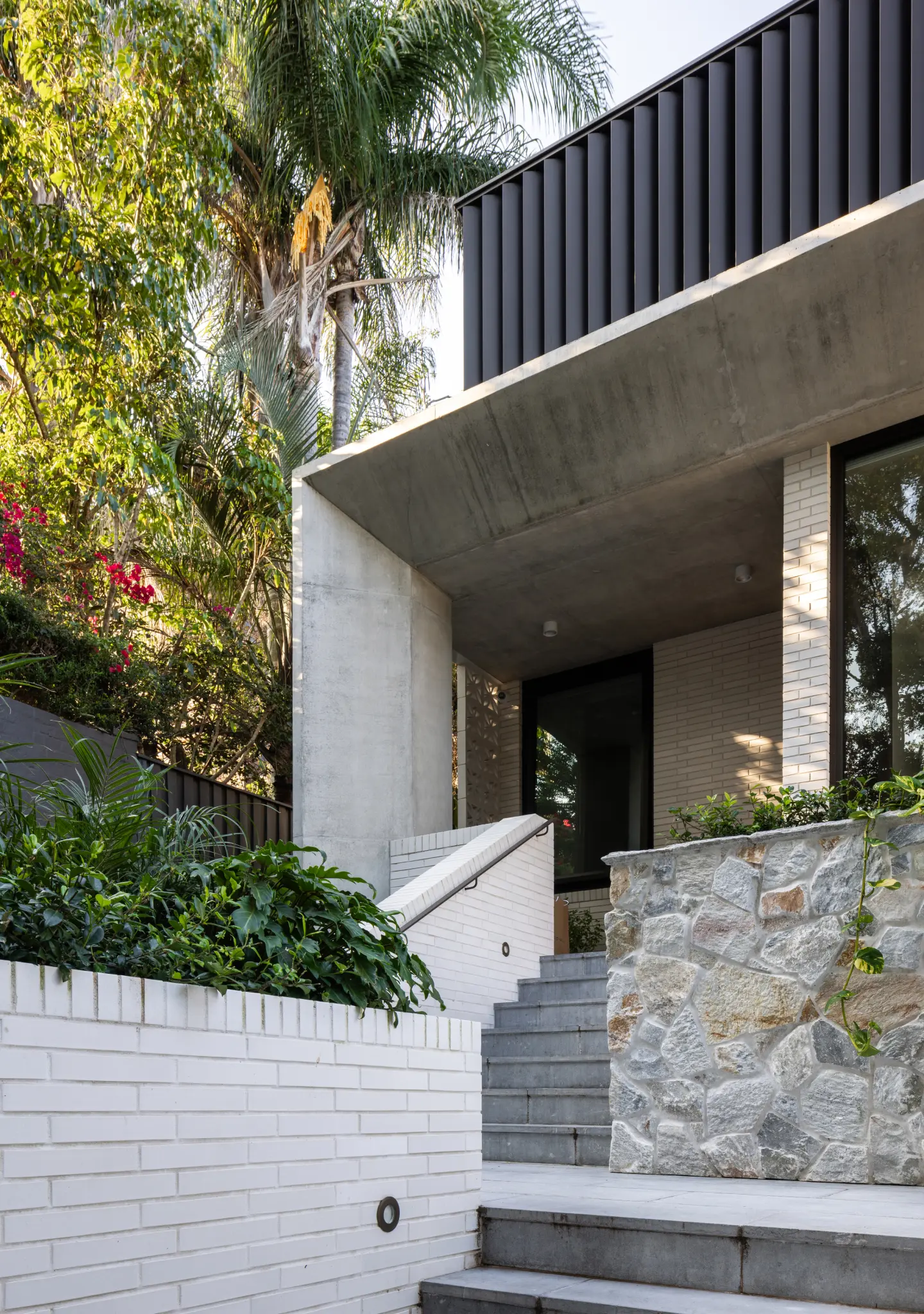 An exterior of the BJB Architects project in Bondi showing the entry steps and stone wall with brick building in the background.