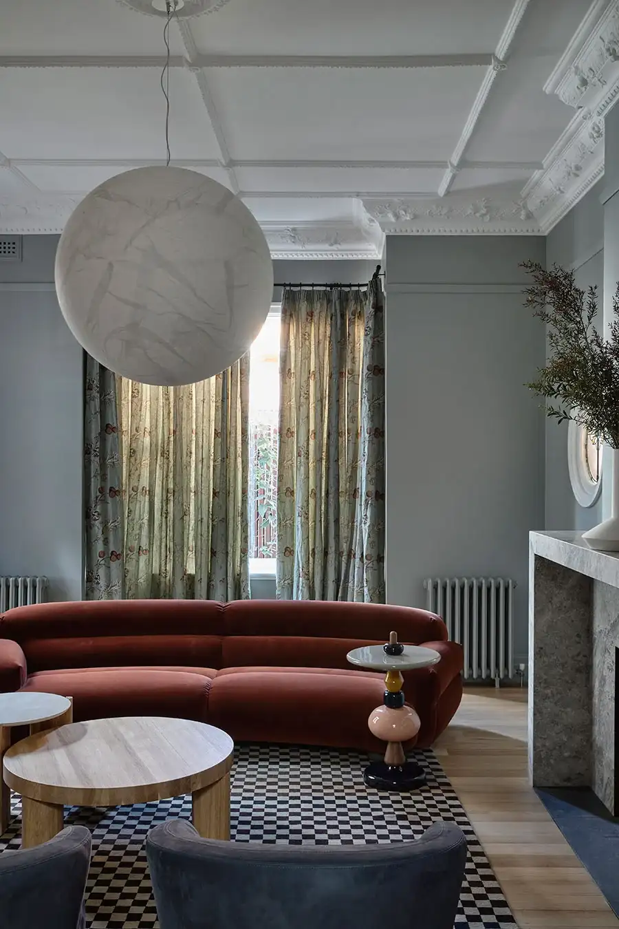 Gascoigne by Lucy Clemenger Architects. Photography by Derek Swalwell. Living space with mint grey walls, checkered black and white rug, red curved couch, abstract side table and navy blue finishes. 