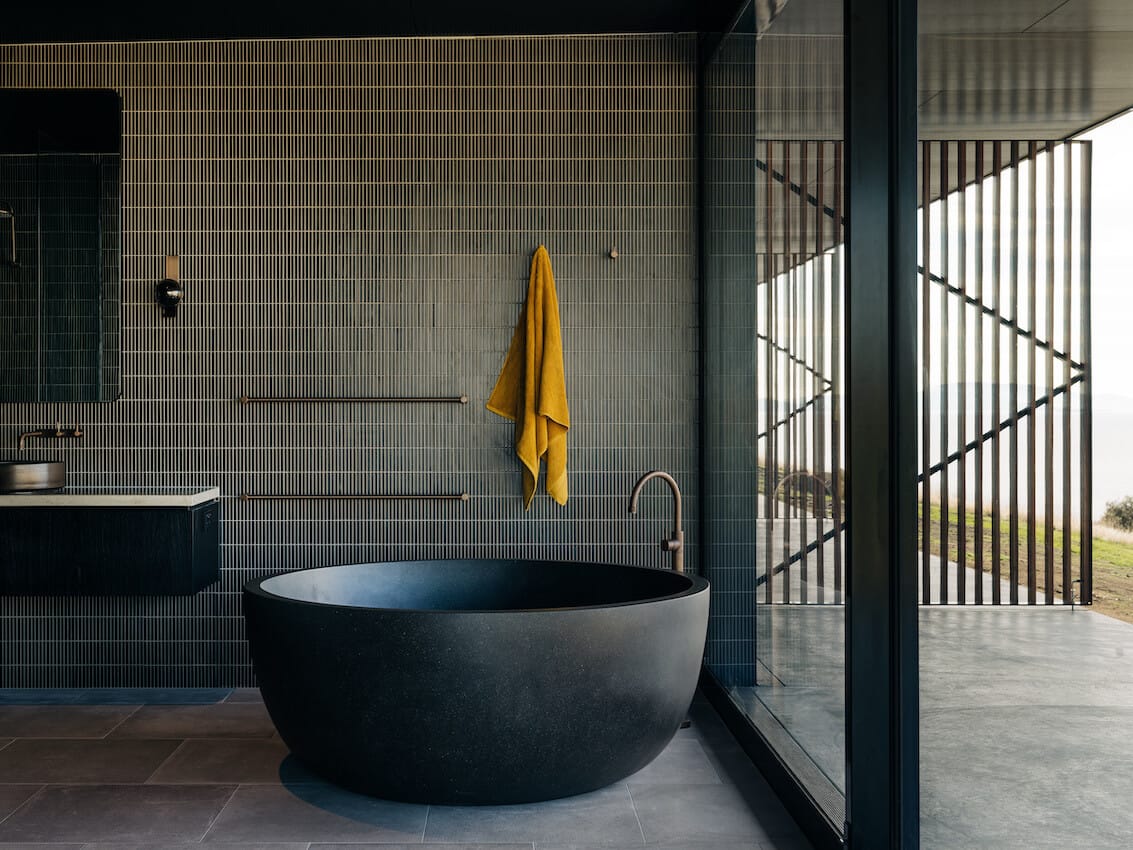 Florida House by Nest Architects with Placement Studio showing a green tile and timber bathroom with a garden outlook