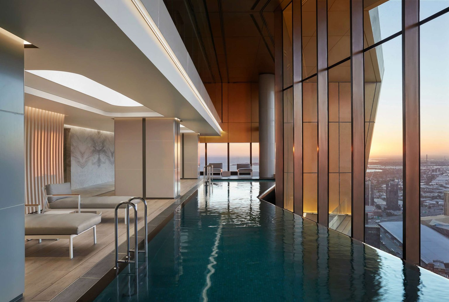 Australia 108 by FK. Photography by Peter Bennetts. Pool and lounge chairs in high-rise multi-residential building with views across the city. 
