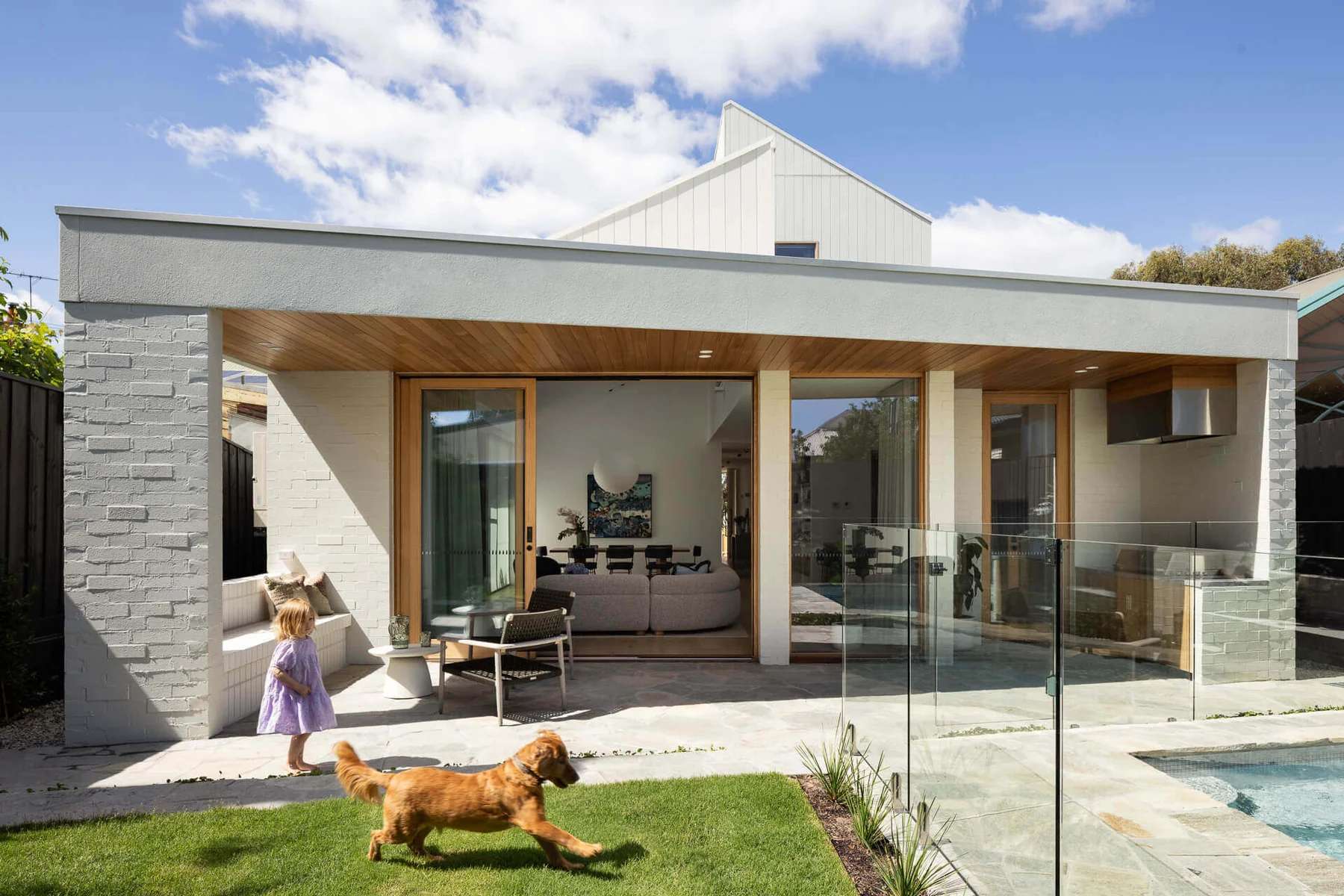 Princes Light House by BENT Architecture. Photography by Tatjana Plitt. Sunken living space with hanging fireplace, tan leather couch and a window overlooking agranny flat in the backyard. 