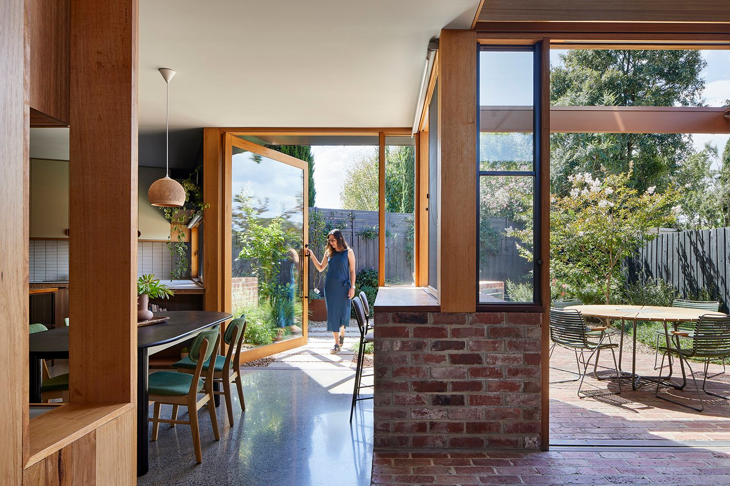 Terracotta House by R Architecture. Photography by Matt C. Living space with grey carpets and full height windows, with a mum and a baby playing on front of window.