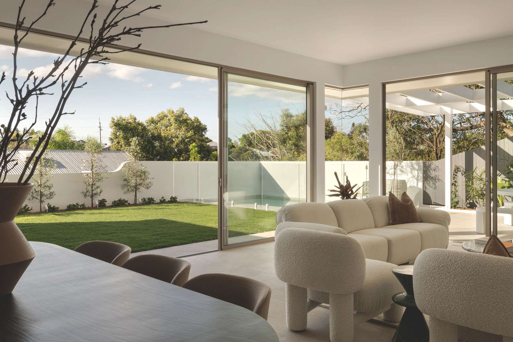 Paddington Terrace by FURNISHD. Photography by Dylan James. Living room opening onto courtyard and patio with white outdoor seating. 