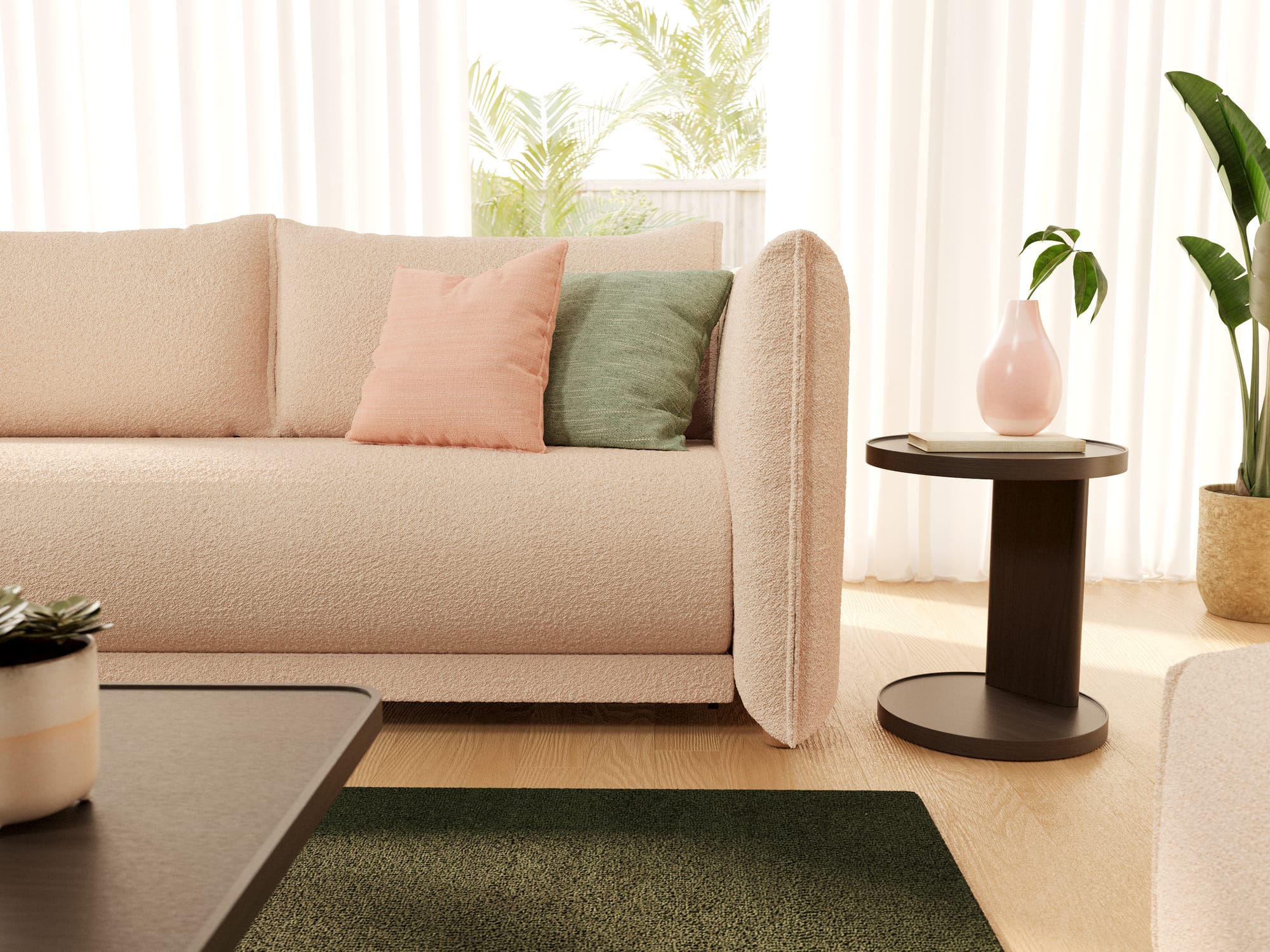 Byron Sofa Bed in Sand Bank by Koala.  Close up of a pink boucle couch with pink and green throw cushions, with a dark green floor rug and dark timber bedside table. 