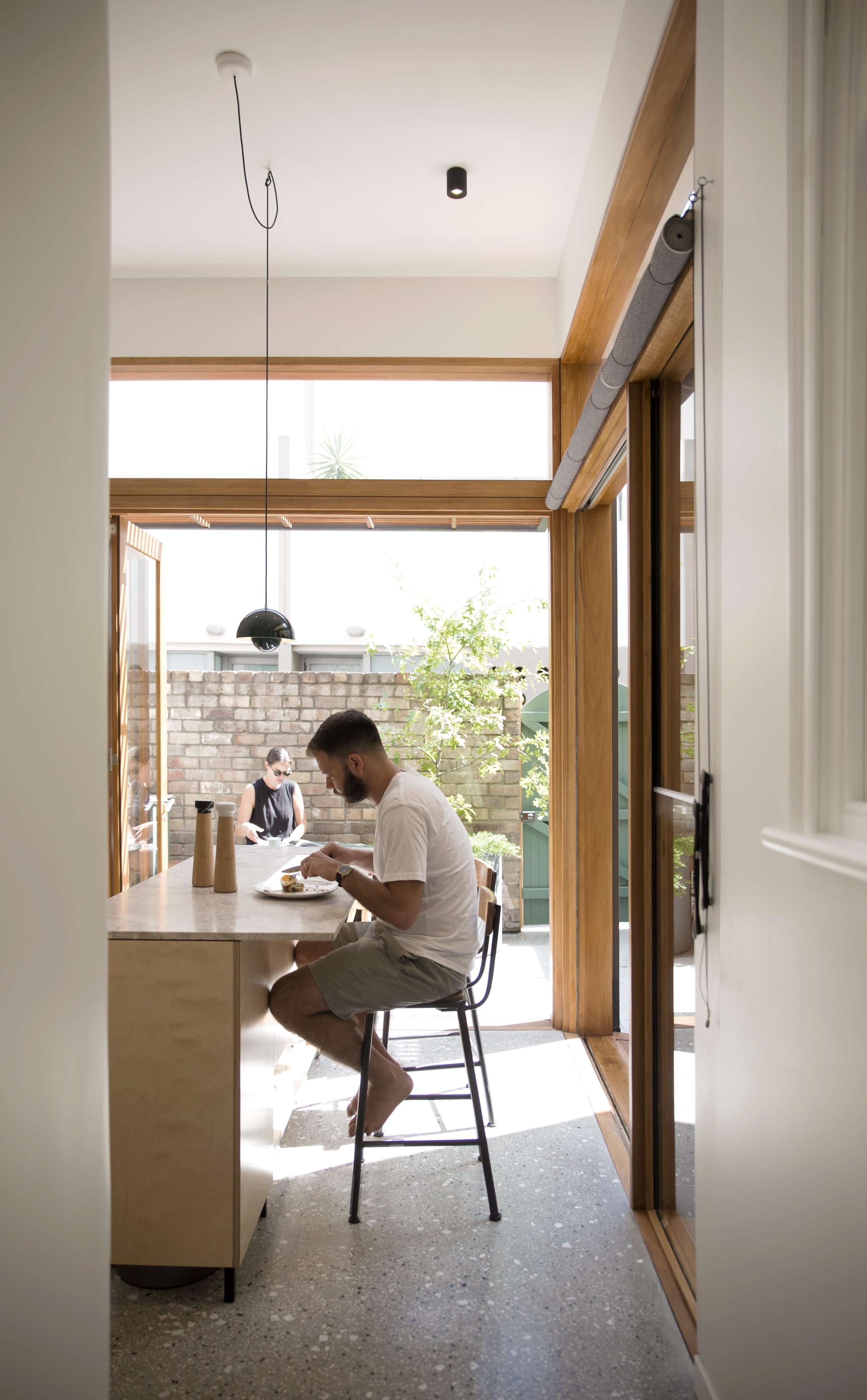 Chippendale Terrace House by Marker Architecture & Design. Photography by Felix Saw. Kitchen with polished concrete flooring and plywood finishes opening onto sunny courtyard with reclaimed brick wall and green gate.