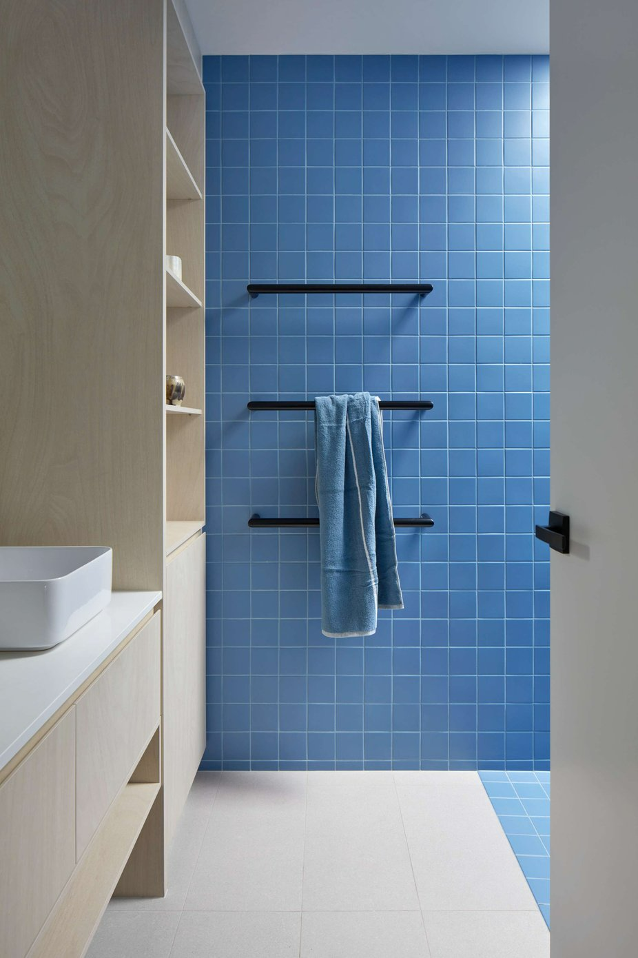 Small House by R Architecture. Photography by Jack Lovel. Bathroom with light plywood cabinetry, electric blue wall and floor tiles and black accents.