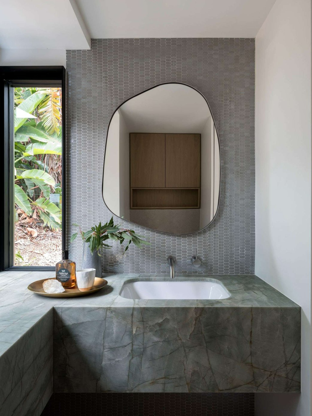 Palm 01 by Watershed Architects. Photography by Tom Ferguson. Green marbled floating counter, mosaic matte grey wall tiles and abstract shaped wall mirror. 