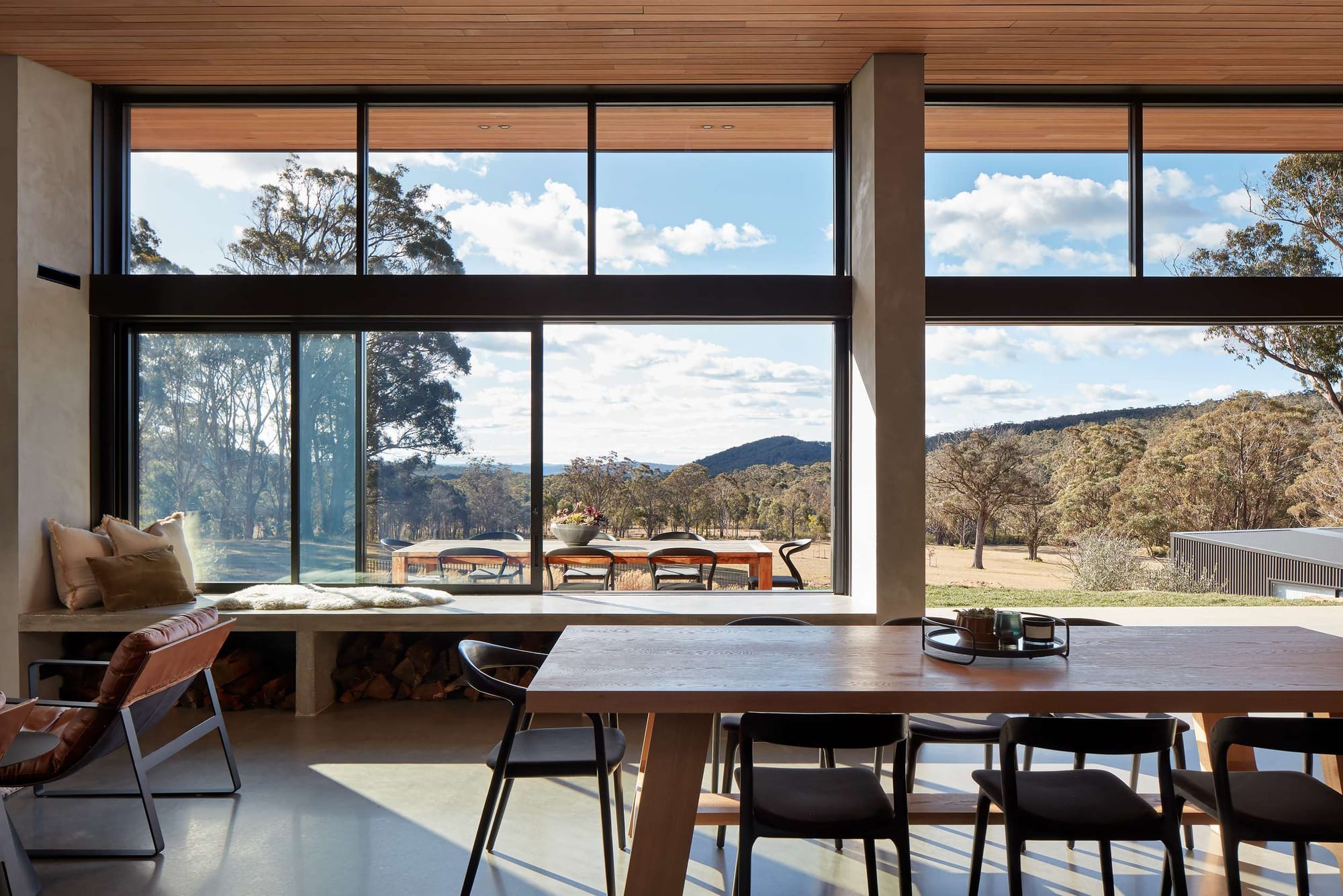 House Woodlands by AO Design Studio. Photography by Luc Remond. Open plan living and dining area opening onto rolling native hills and bushland.