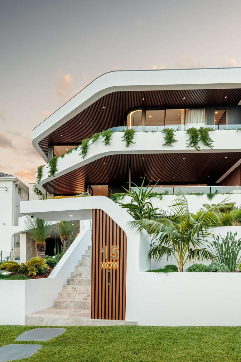 Port Hacking II by 868 Architects. Photographer undisclosed. Facade of multi-level residential home with white render finish, timber detailing and hanging gardens.