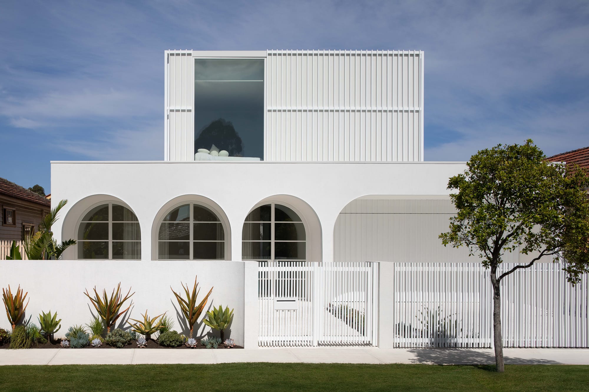 Alba House by Taouk Architects. Photography by Emily Bartlett. Facade of white double-storey home with curved windows.