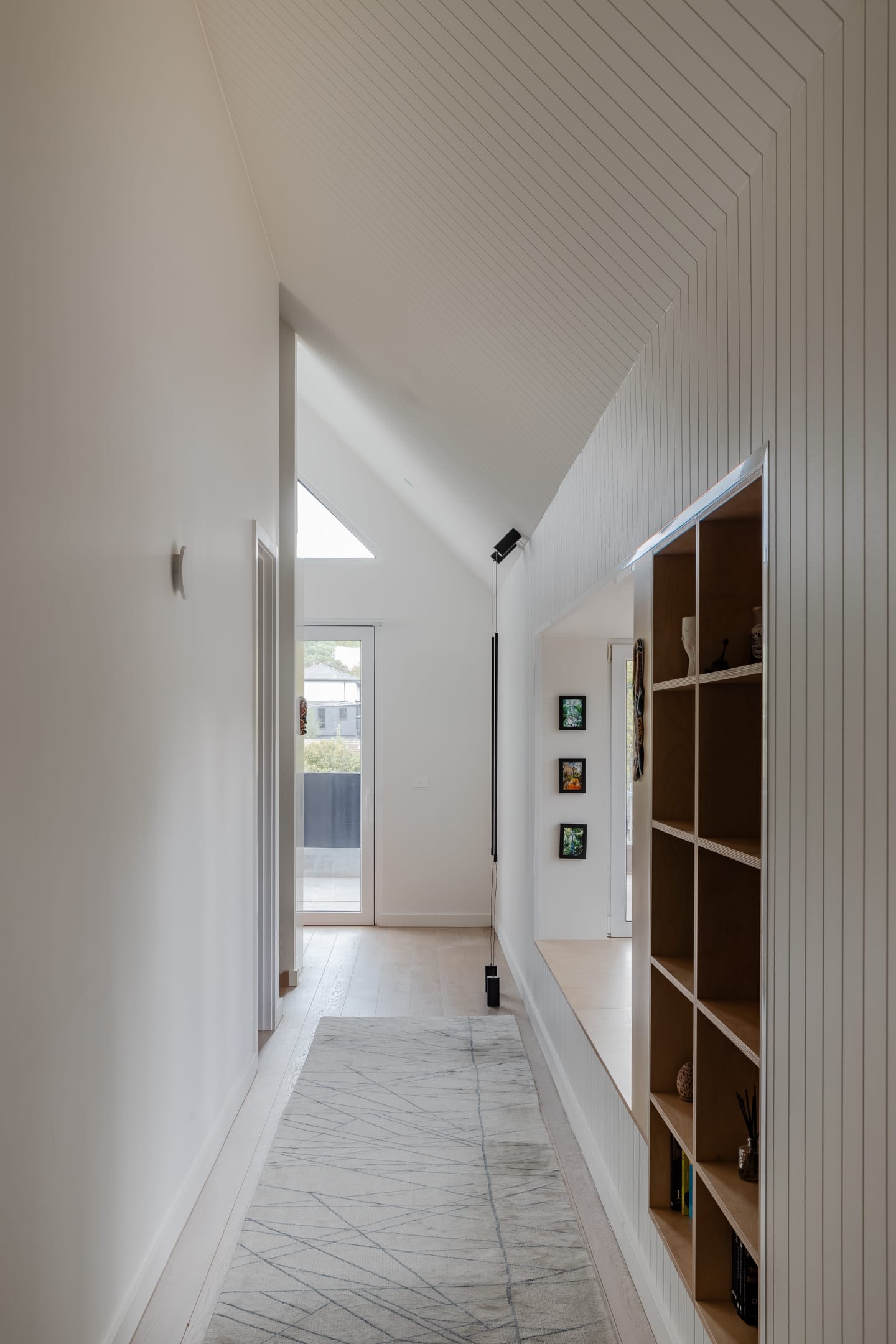 TREE HOUSE by R Architecture. Photography by CM Photography. Hallway with built-in wooden cabinet leading to backyard.